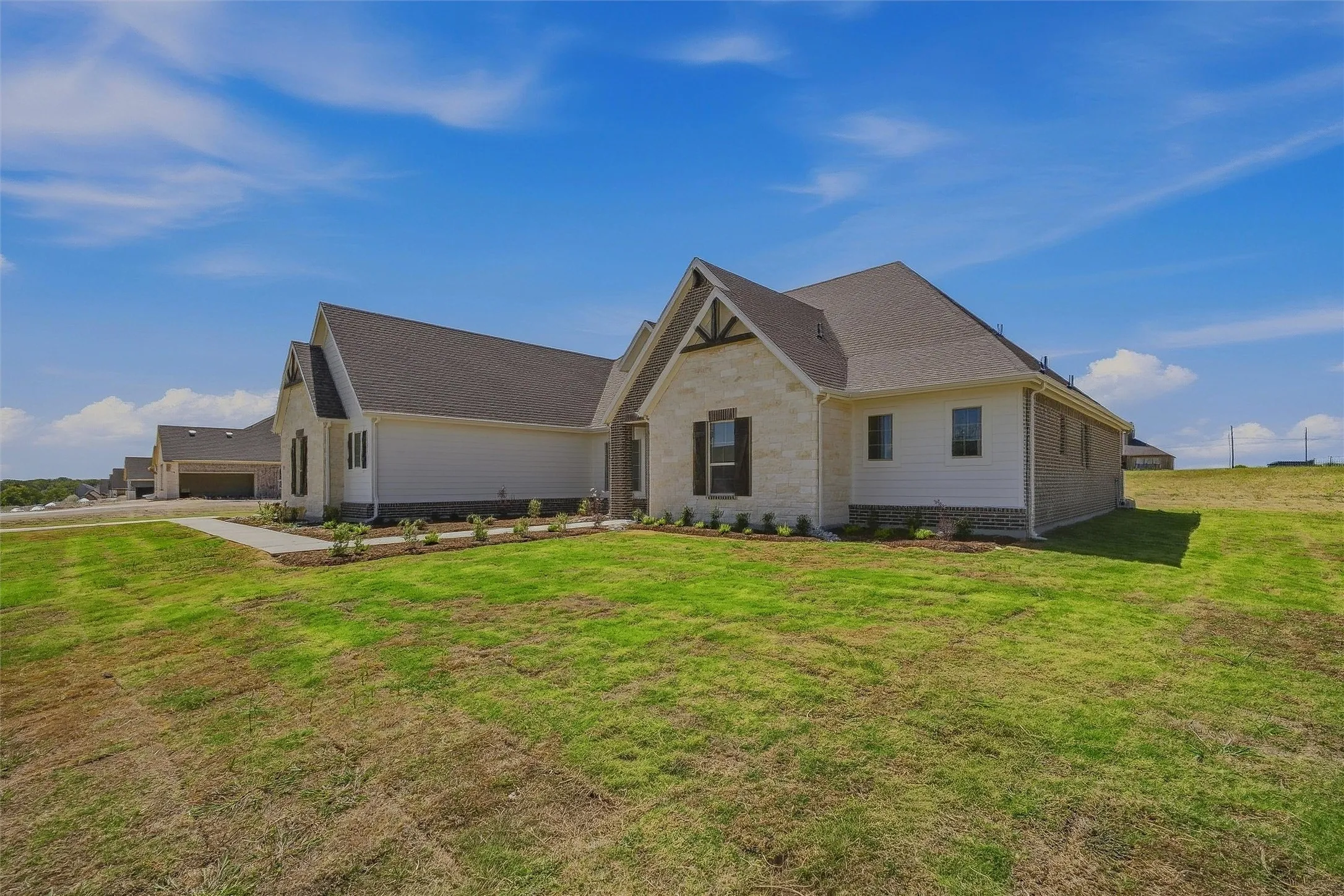 Stone and siding exterior with dark shingle roofing