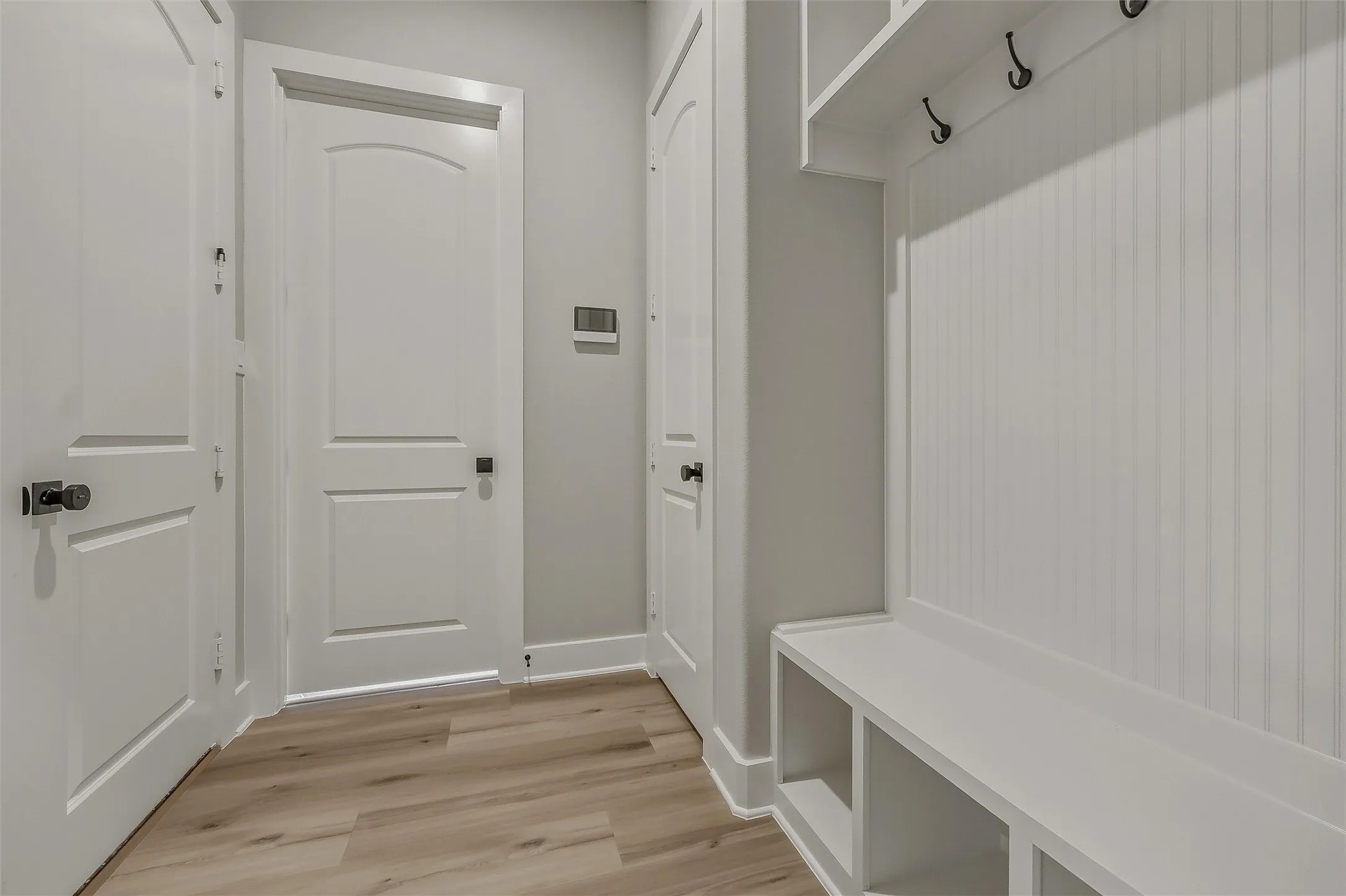 Built-in storage bench with cubbies, beadboard paneling, and coat hooks