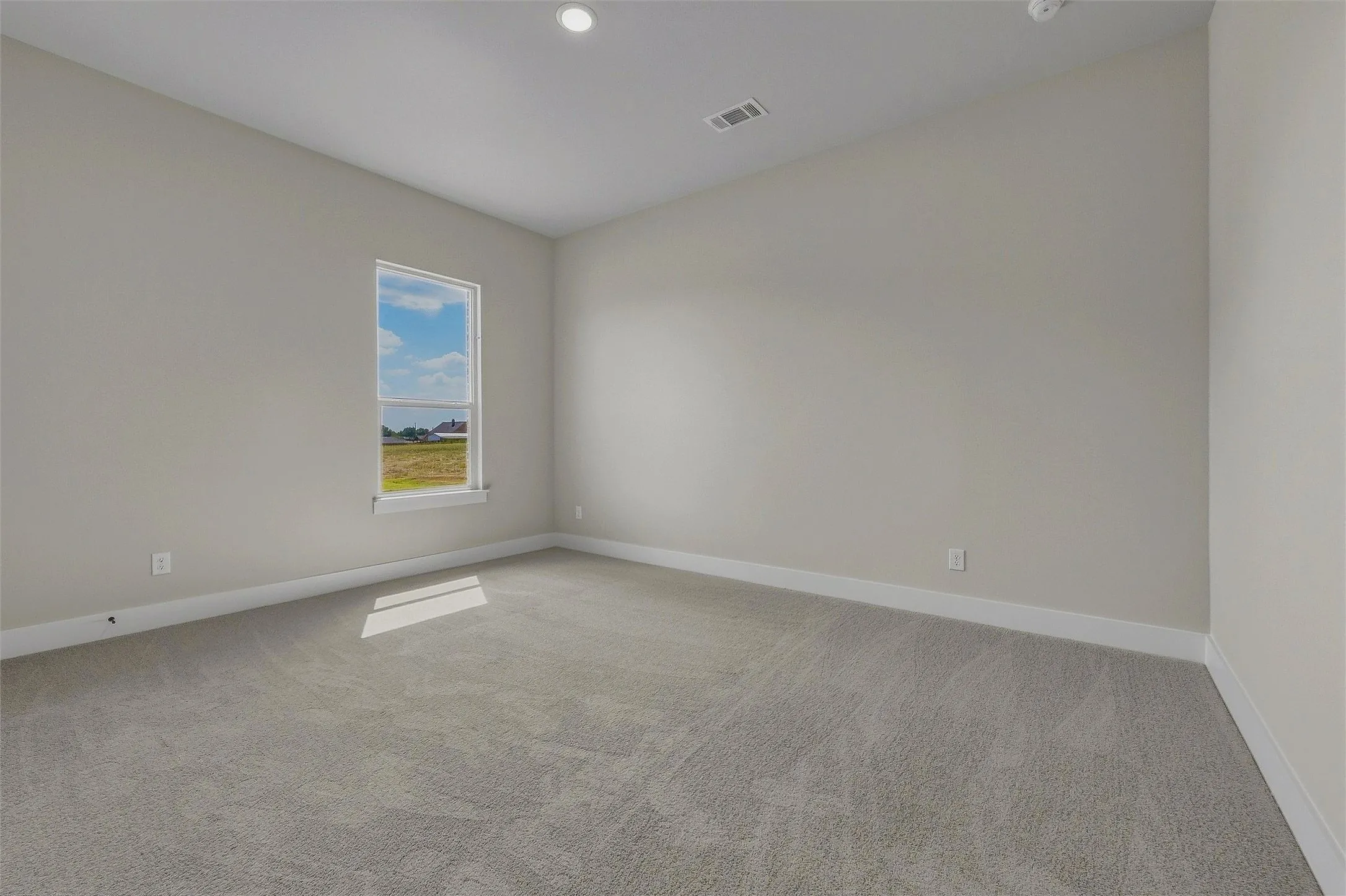 Carpeted flooring with light-toned wall finishes, recessed ceiling lighting, and a single window with exterior scenery