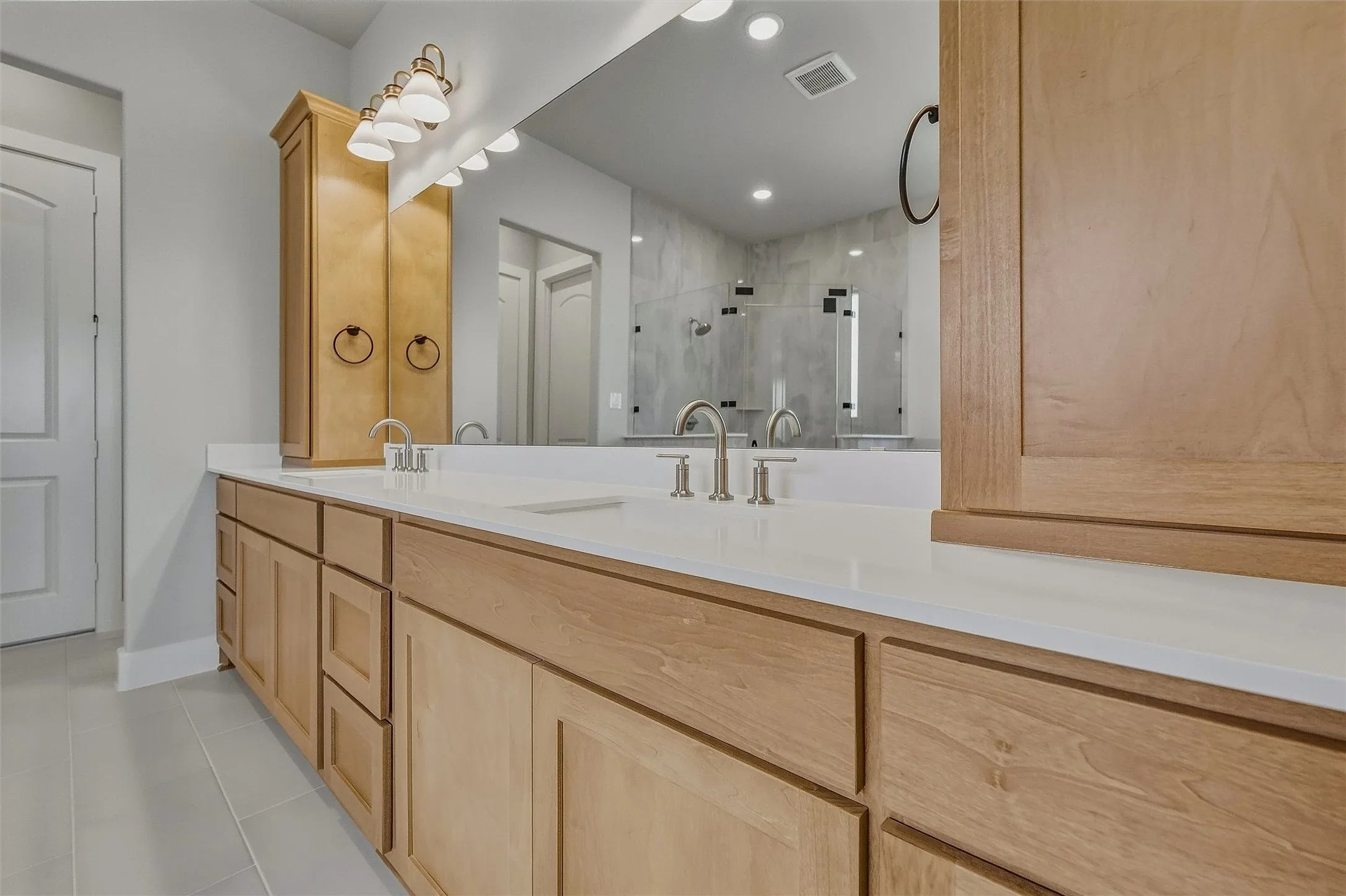 Dual vanity with light wood-finish cabinetry, white countertops, and brushed nickel fixtures