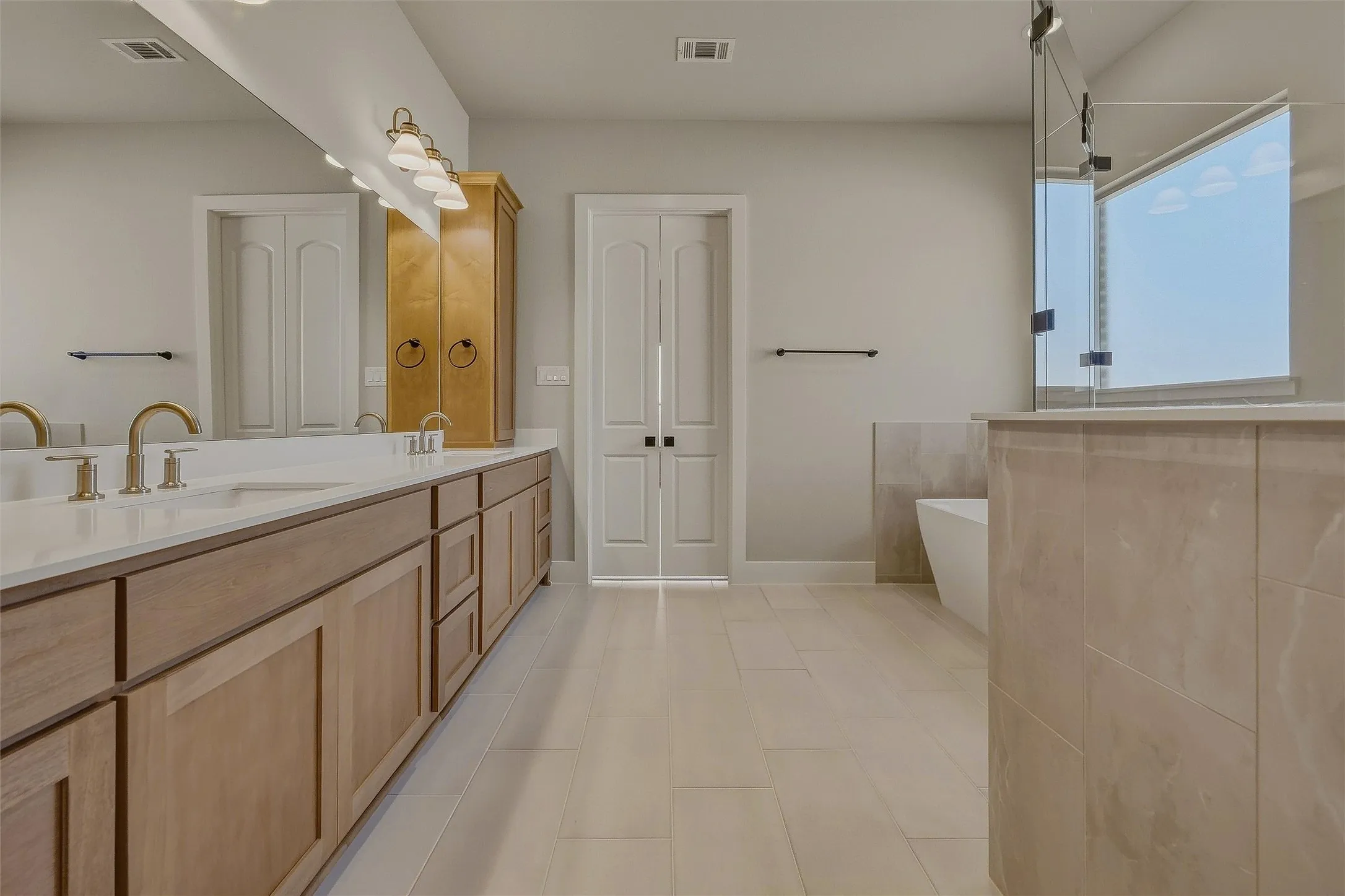 Dual vanity with gold-tone hardware, white countertop, and wood-finish cabinetry