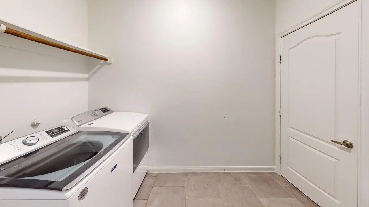 Laundry area featuring a built-in shelf with a hanging rod, tile flooring, and a paneled interior door with brushed nickel hardware