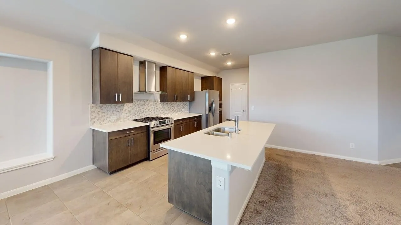 Kitchen featuring a central island with an undermount sink and a stainless steel faucet, dark wood-finish cabinetry, light-toned countertops, a stainless steel range with a matching range hood, and a geometric-patterned tile backsplash