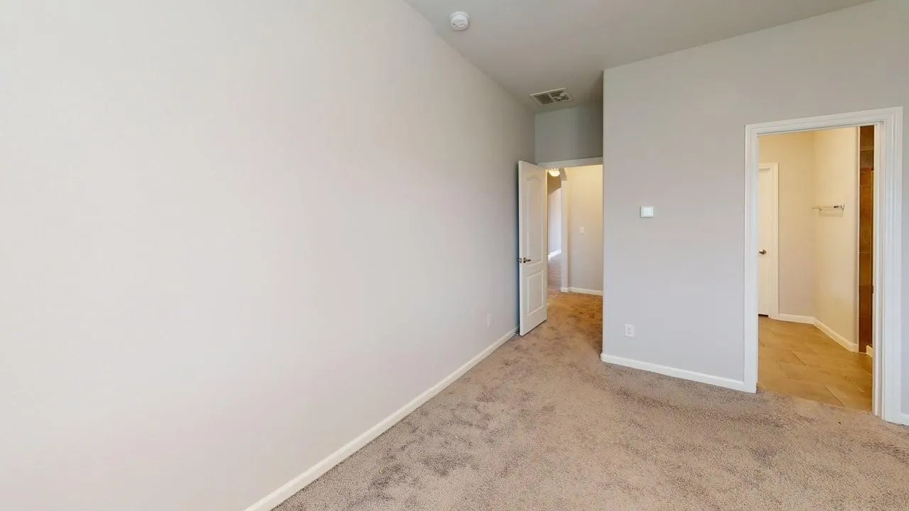 Carpeted room with light neutral wall tones and white baseboards