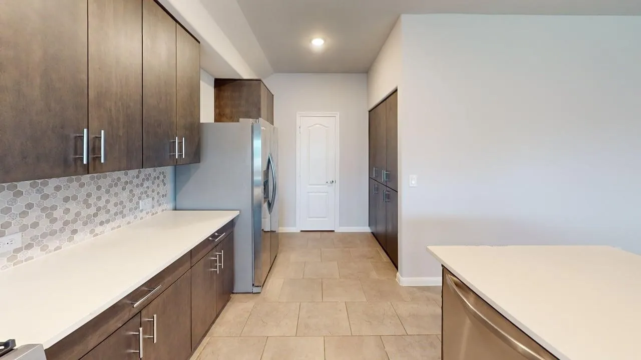 Kitchen featuring dark wood-finish cabinetry, light-toned countertops, and a honeycomb-patterned tile backsplash