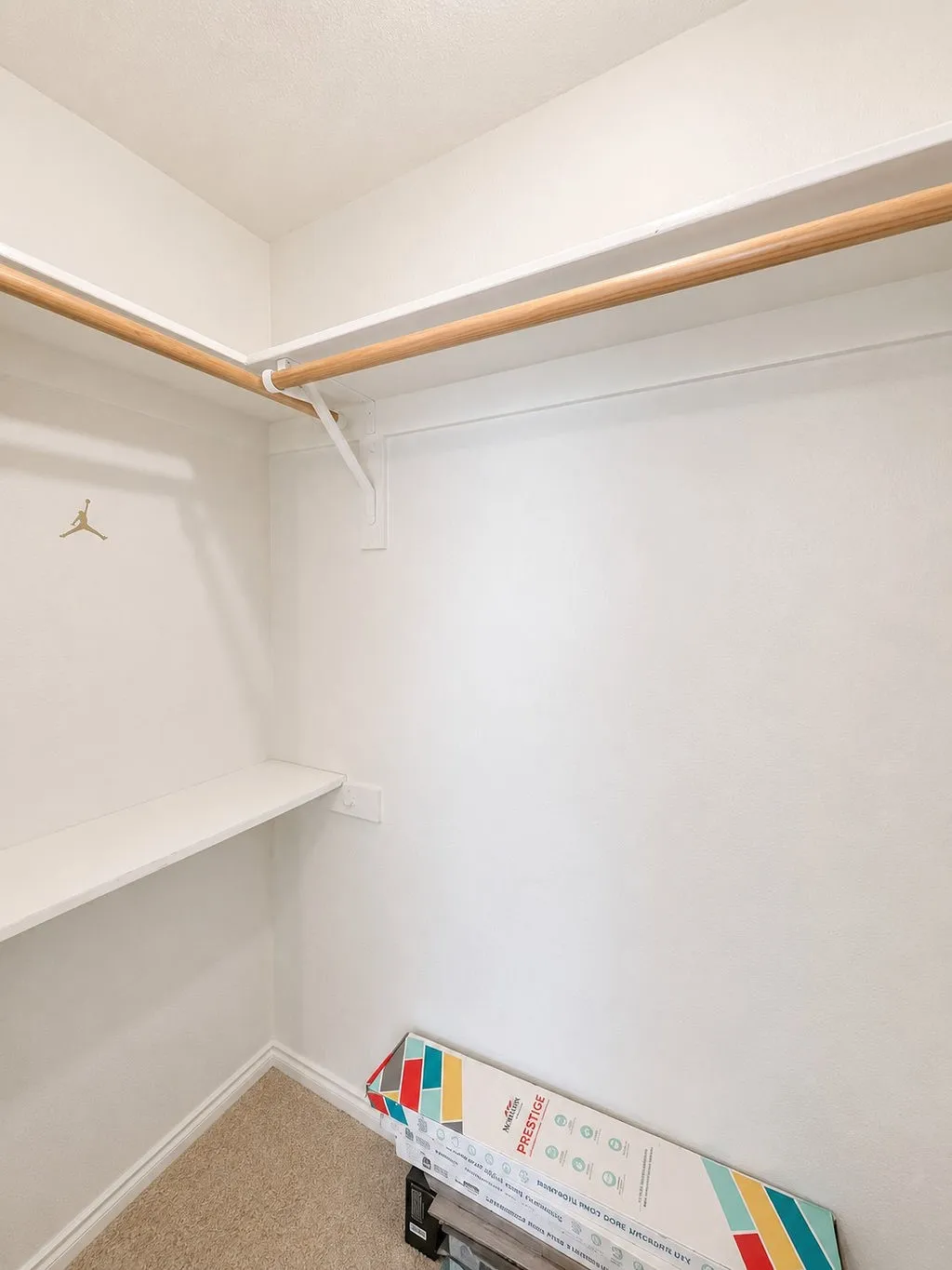 Walk-in closet featuring built-in shelving, two wood closet rods, and carpet flooring