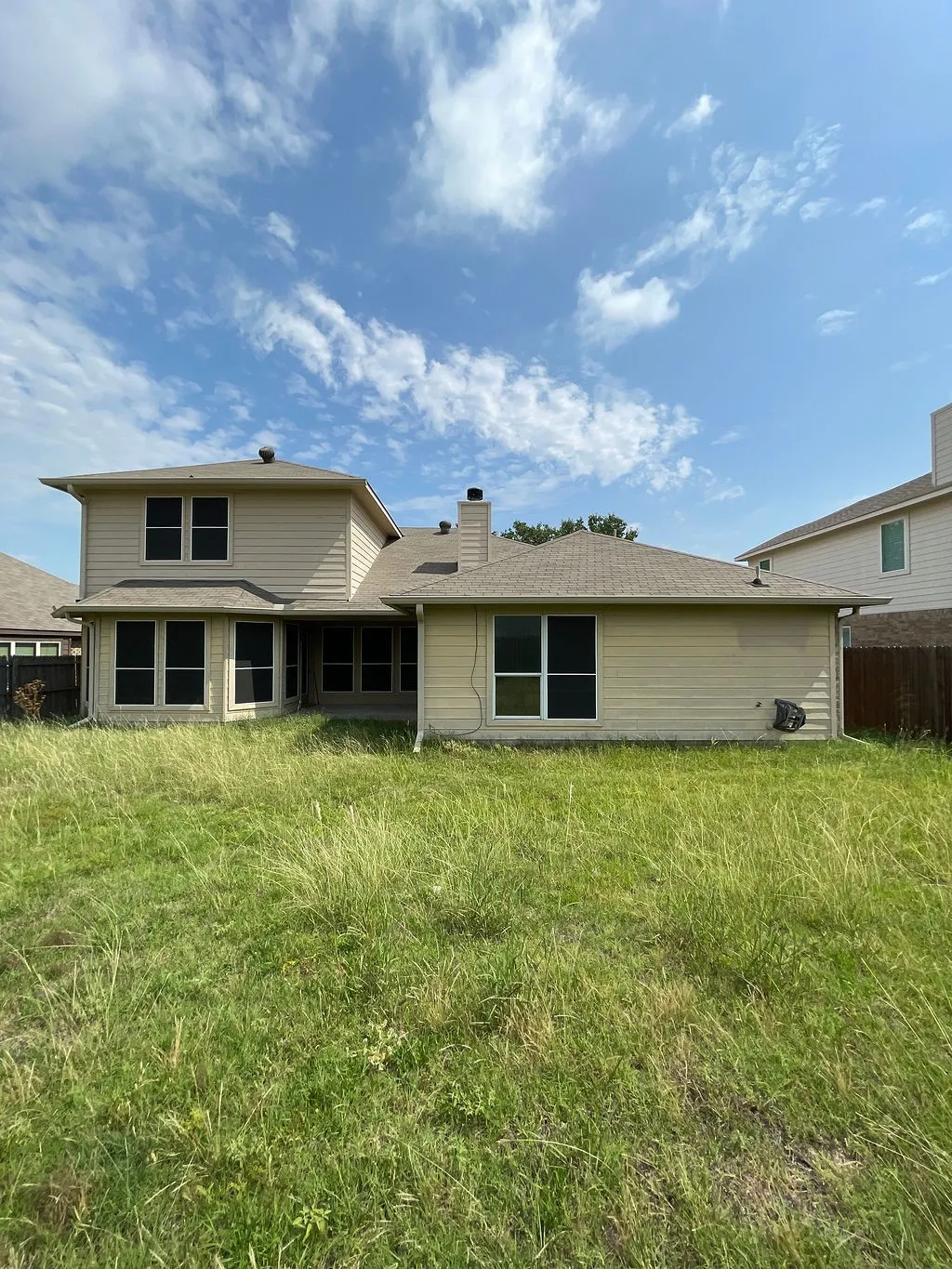 (original photo)Rear exterior featuring light-colored siding, a multi-level roofline, and multiple windows