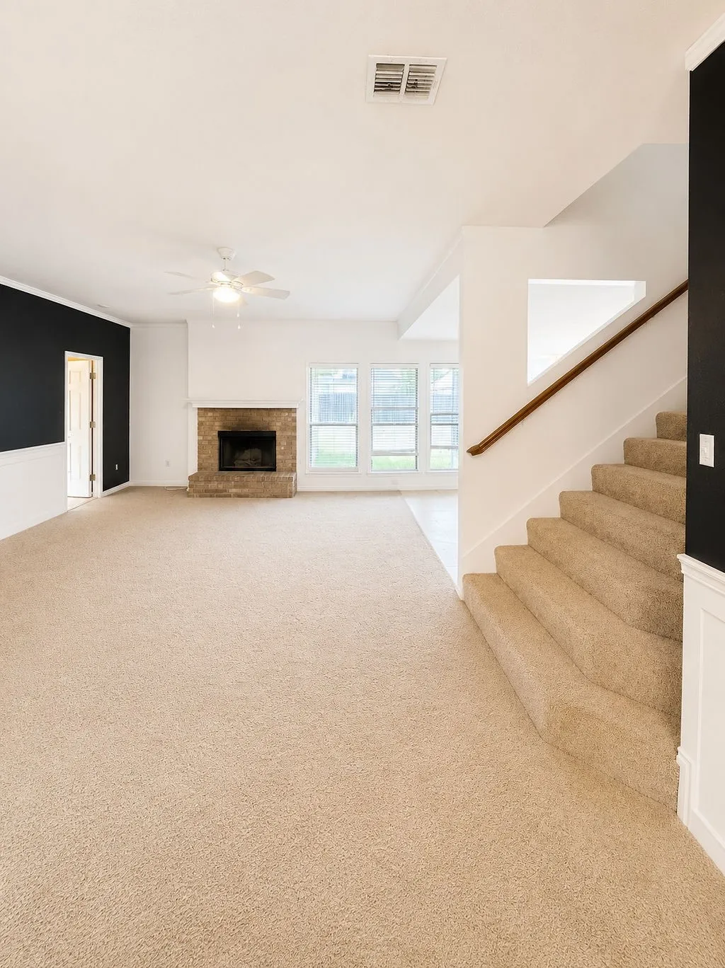 Open-concept living space featuring a brick fireplace, ceiling fan, and large windows
