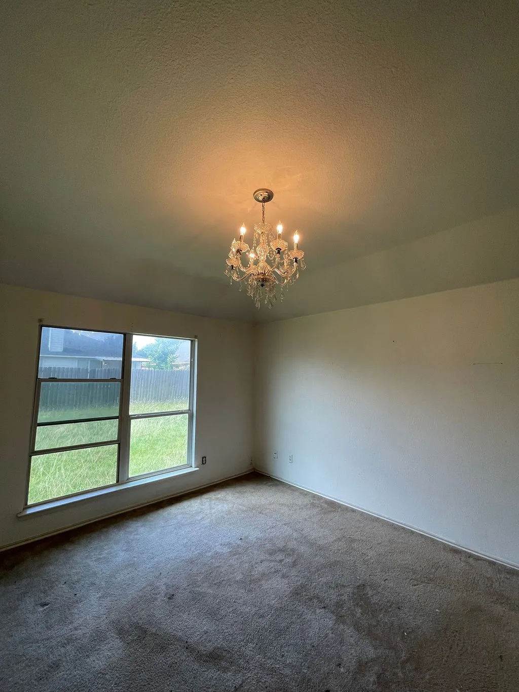 (original photo)Clear glass chandelier with five candelabra-style lights provides overhead illumination