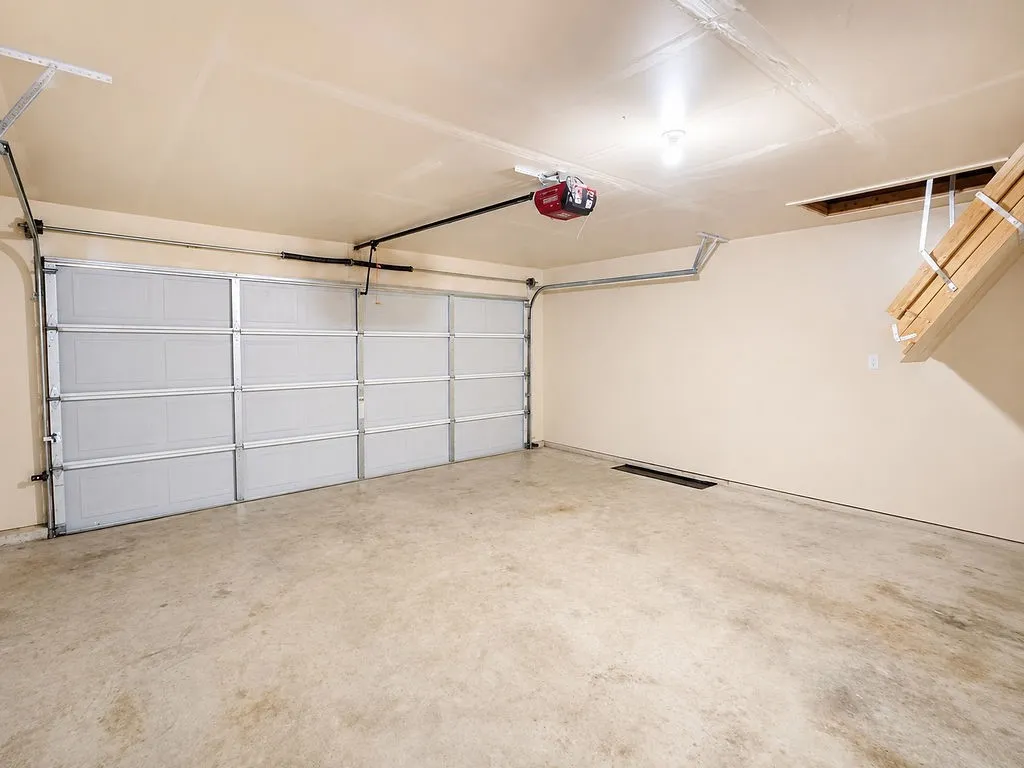 Spacious garage featuring a concrete floor, a paneled overhead door, and an automatic garage door opener