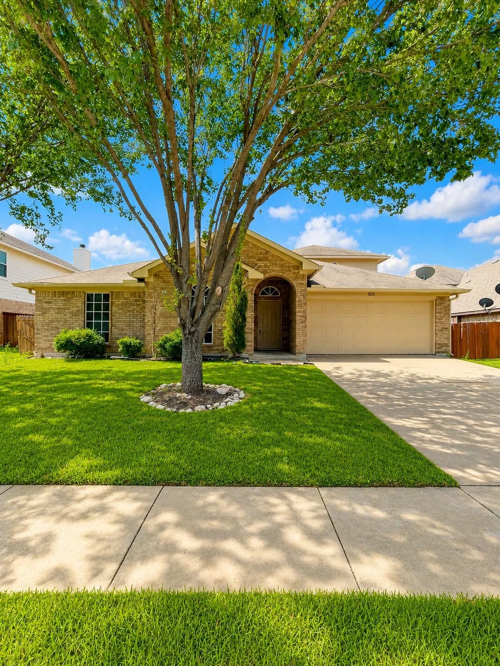 Traditional brick facade with an arched entry, a two-car garage, and a manicured lawn