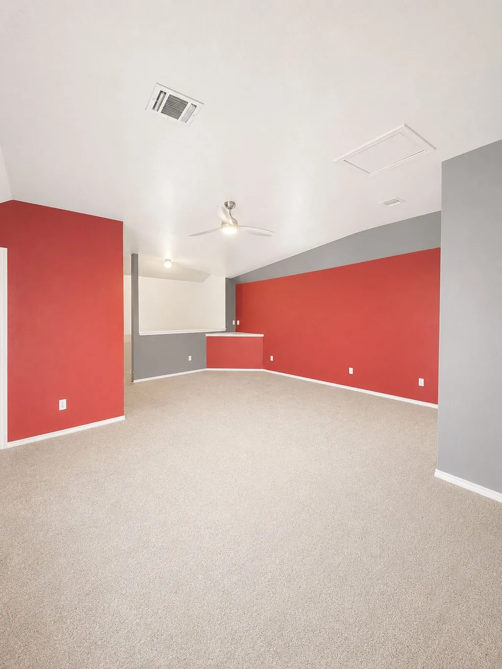 Spacious room featuring neutral carpet flooring and a vaulted ceiling