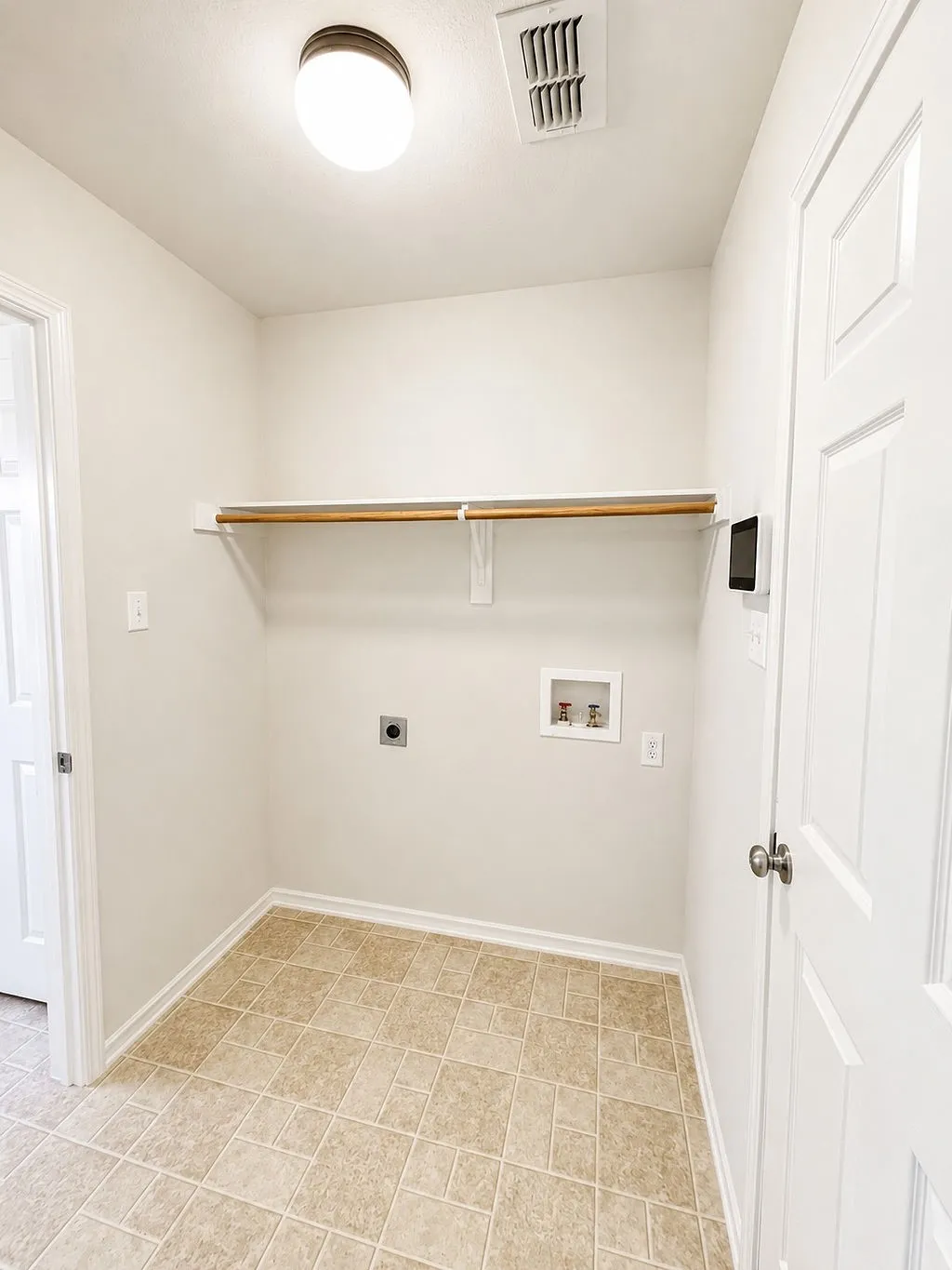 Utility room featuring a built-in shelving rod, neutral-toned walls, patterned tile flooring, and a flush-mount ceiling light