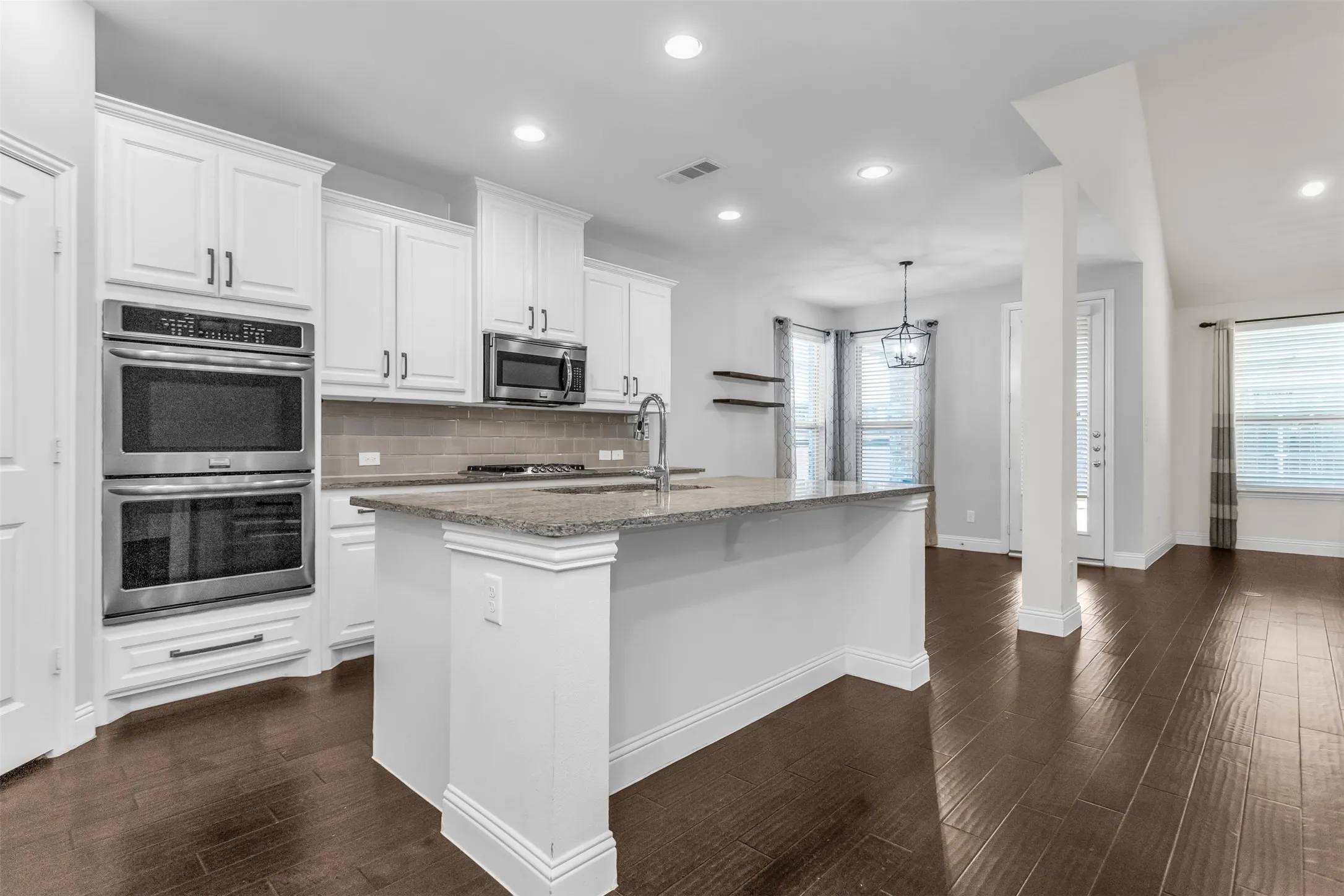 Modern kitchen featuring white cabinetry, stainless steel double ovens, a built-in microwave, and a gas cooktop