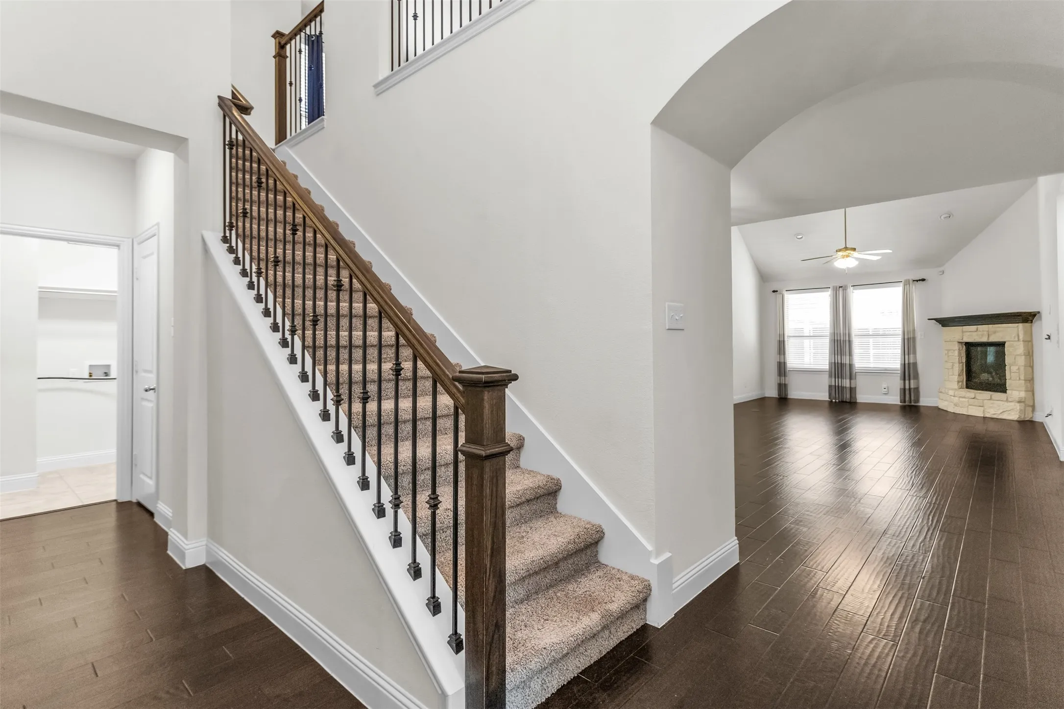 Grand staircase featuring wood railings, wrought iron balusters, and carpeted treads