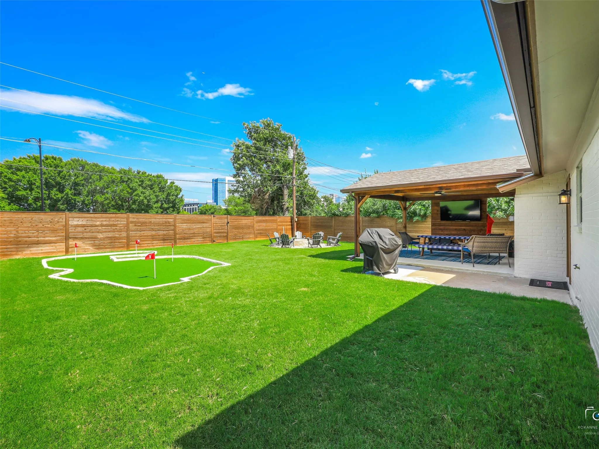 Large backyard with covered patio, putting green and firepit