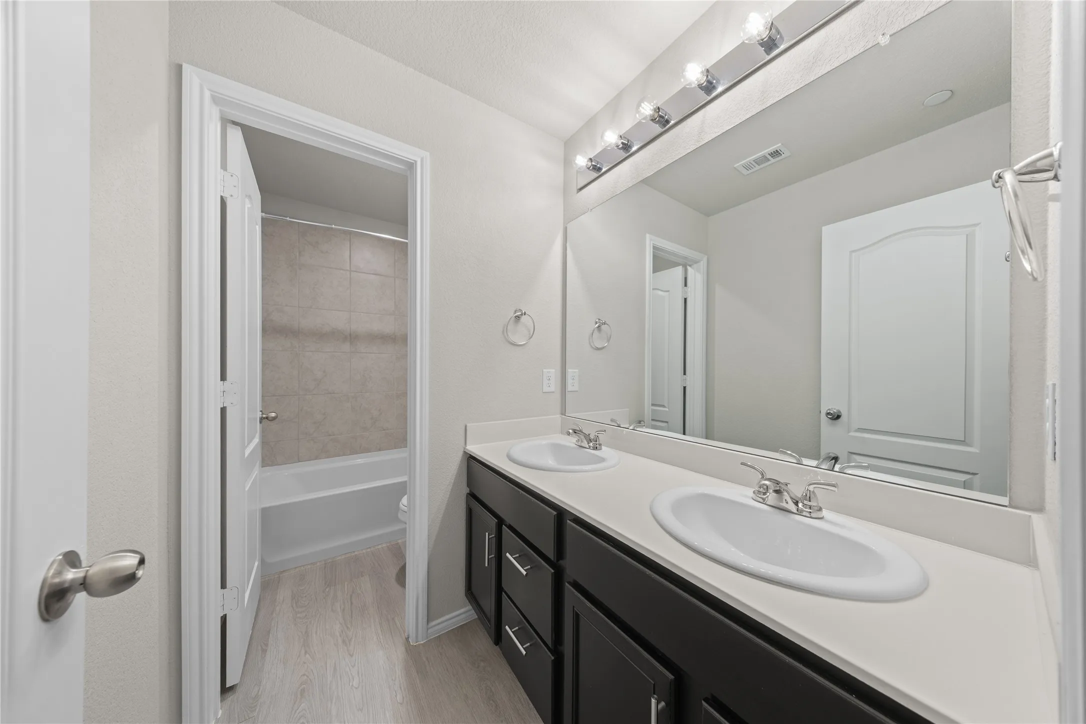 Bathroom featuring a double vanity with dark cabinetry, light countertops, and individual oval sinks