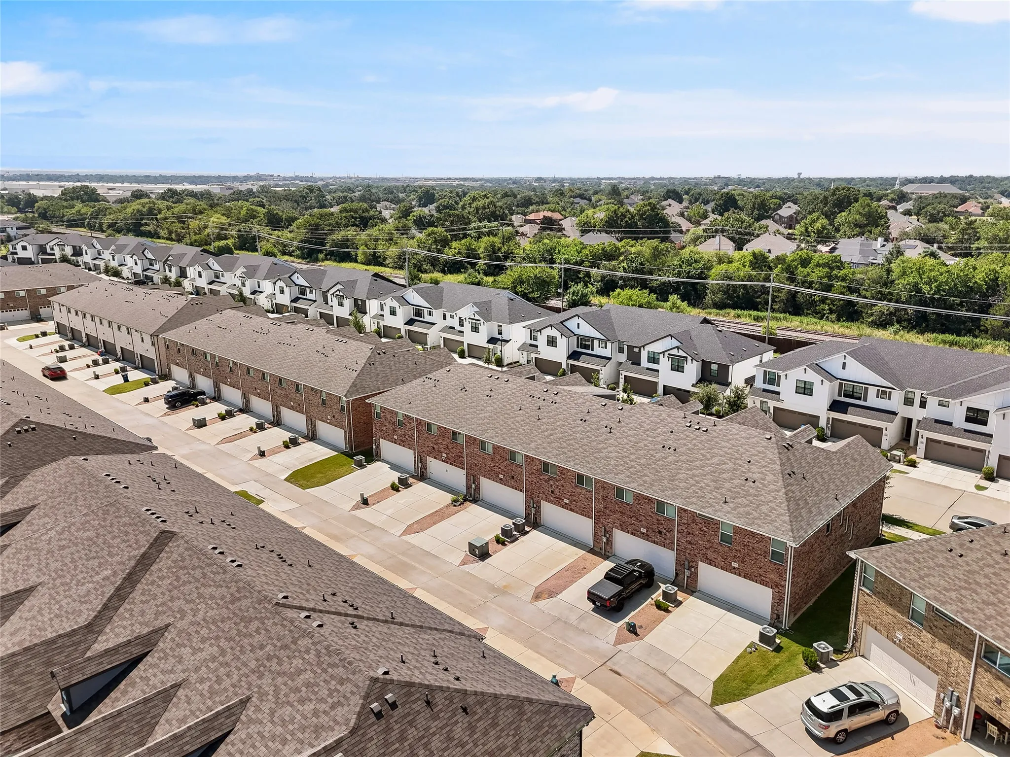 Modern townhome community featuring contemporary architectural design with clean lines, dark asphalt roofing, and brick façade detailing
