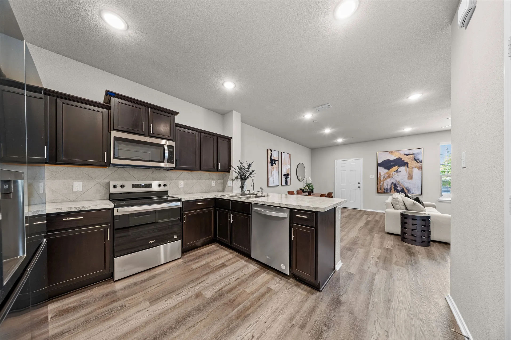 Modern kitchen featuring dark cabinetry with stainless steel appliances, including a gas range and dishwasher, paired with a subway tile backsplash