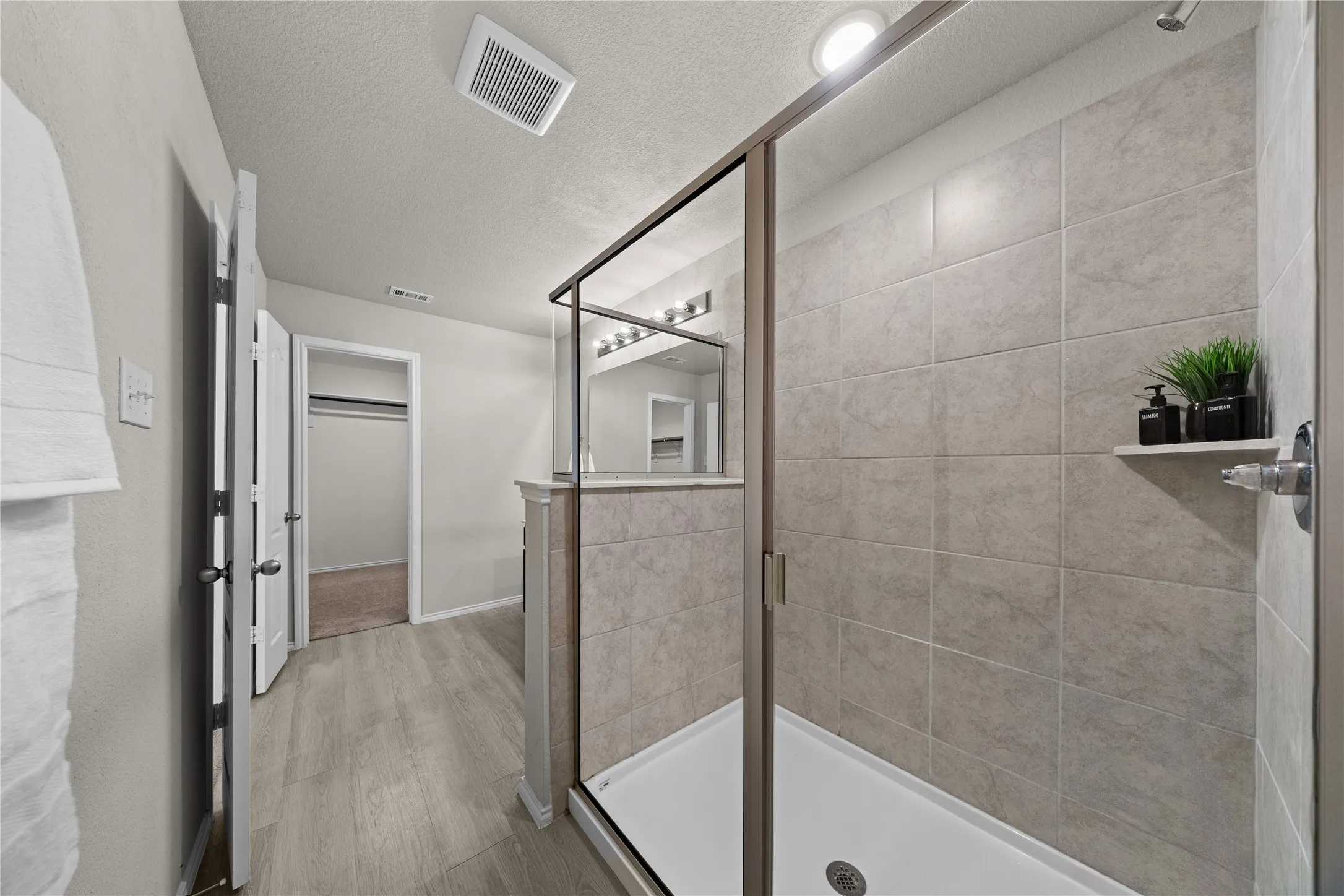 Glass-enclosed shower featuring large format tile walls and a built-in shower niche