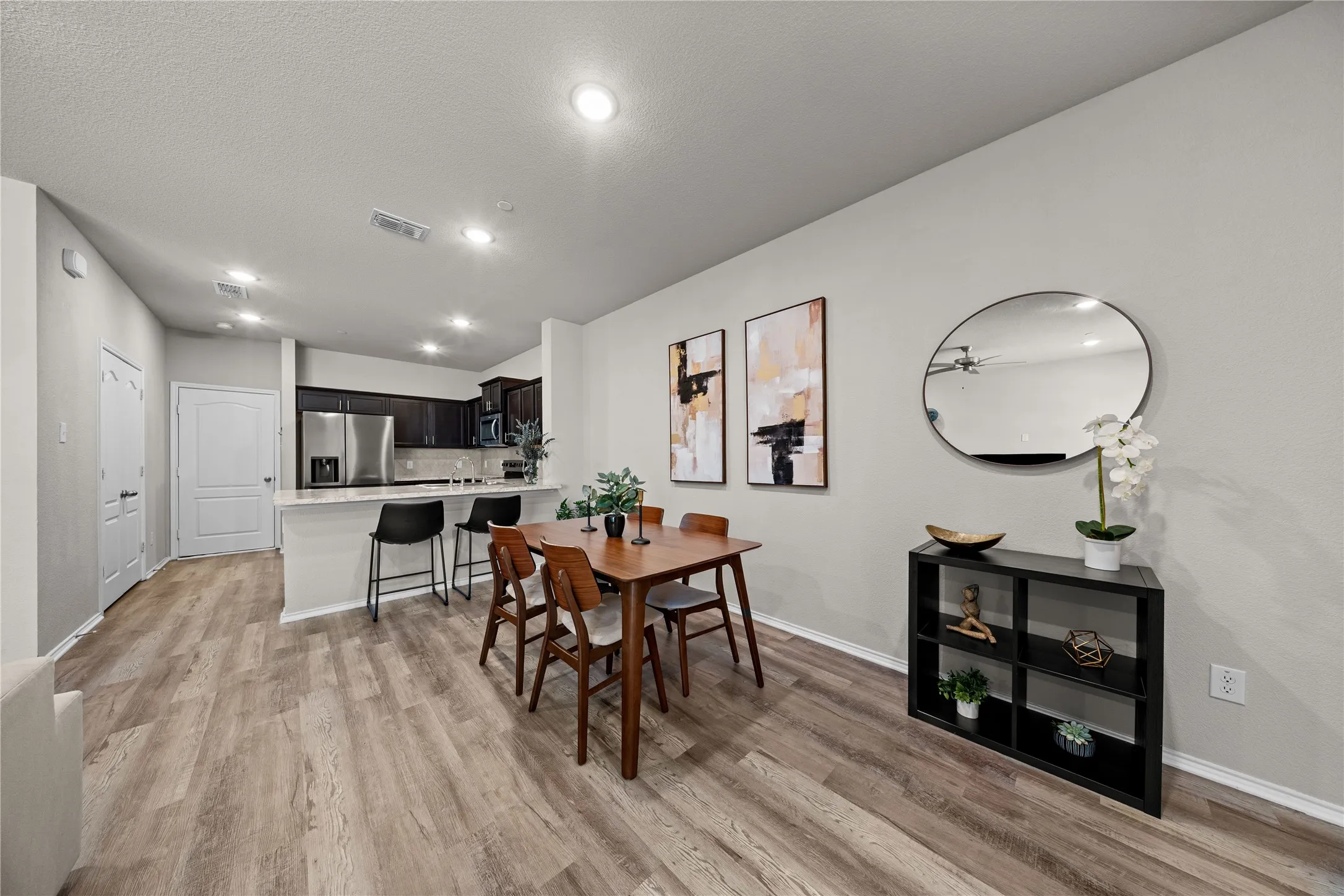 Open-concept living space featuring wood-finish flooring throughout, recessed ceiling lighting, and a dining area with wood table and chairs