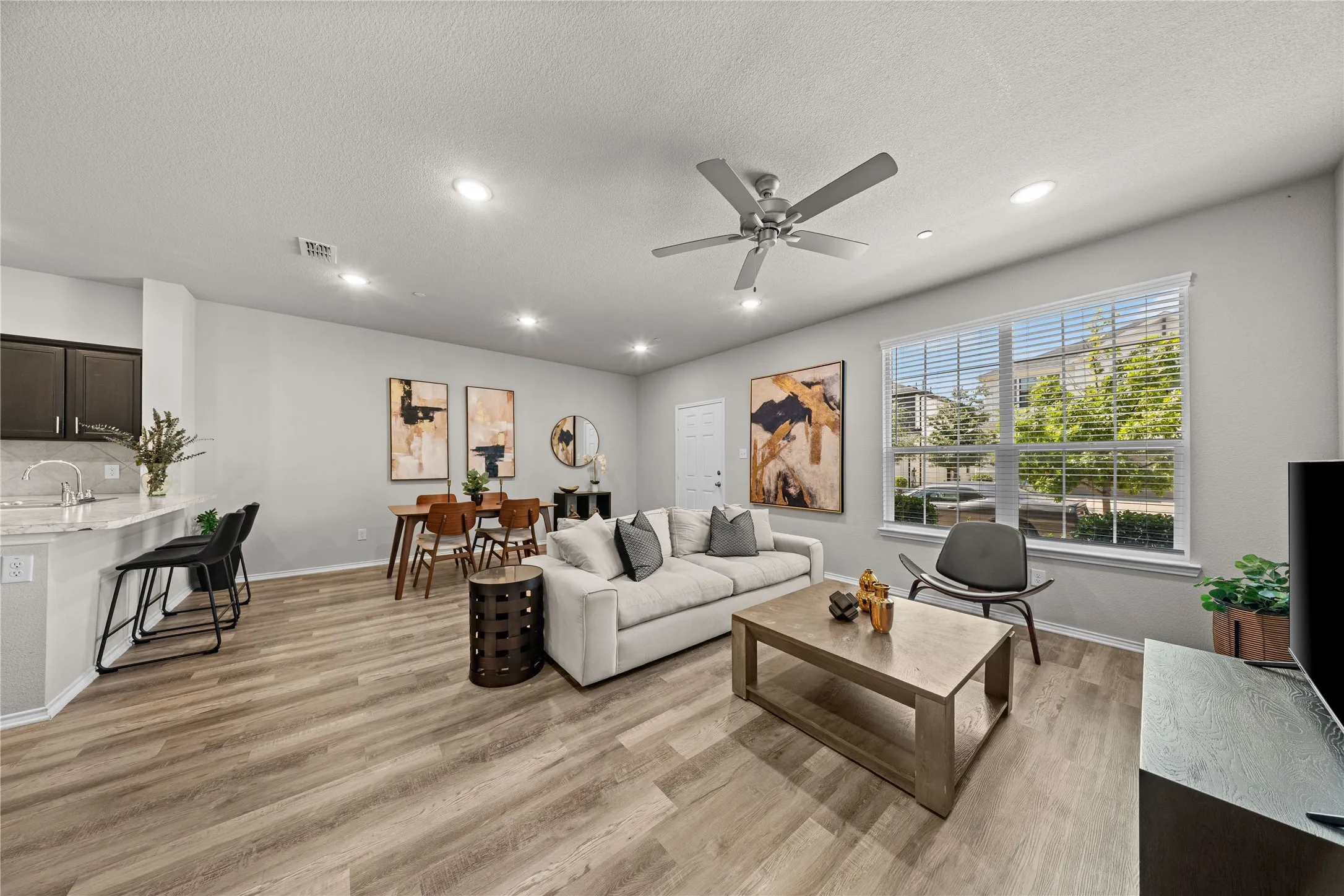 Open-concept living space showcasing wood-finish flooring, recessed ceiling lighting, and a ceiling fan