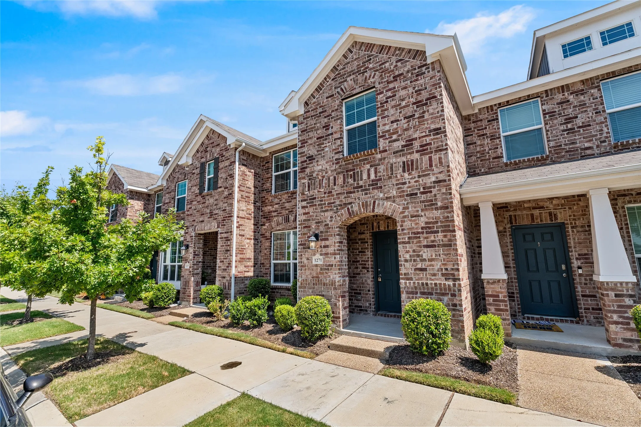 Brick exterior facade with white trim accents and dark entry doors