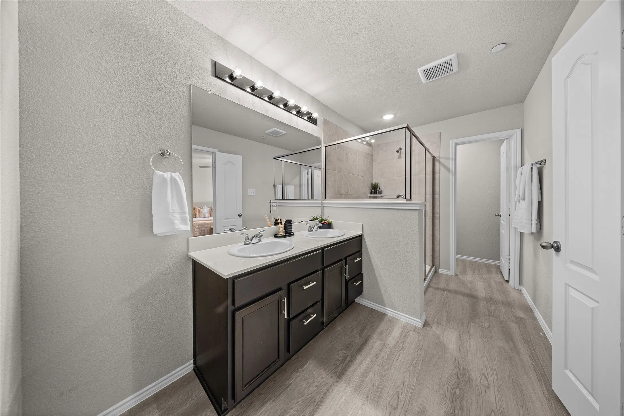 Dual sink vanity with dark wood-finish cabinetry, light-toned countertop, and individual oval sinks