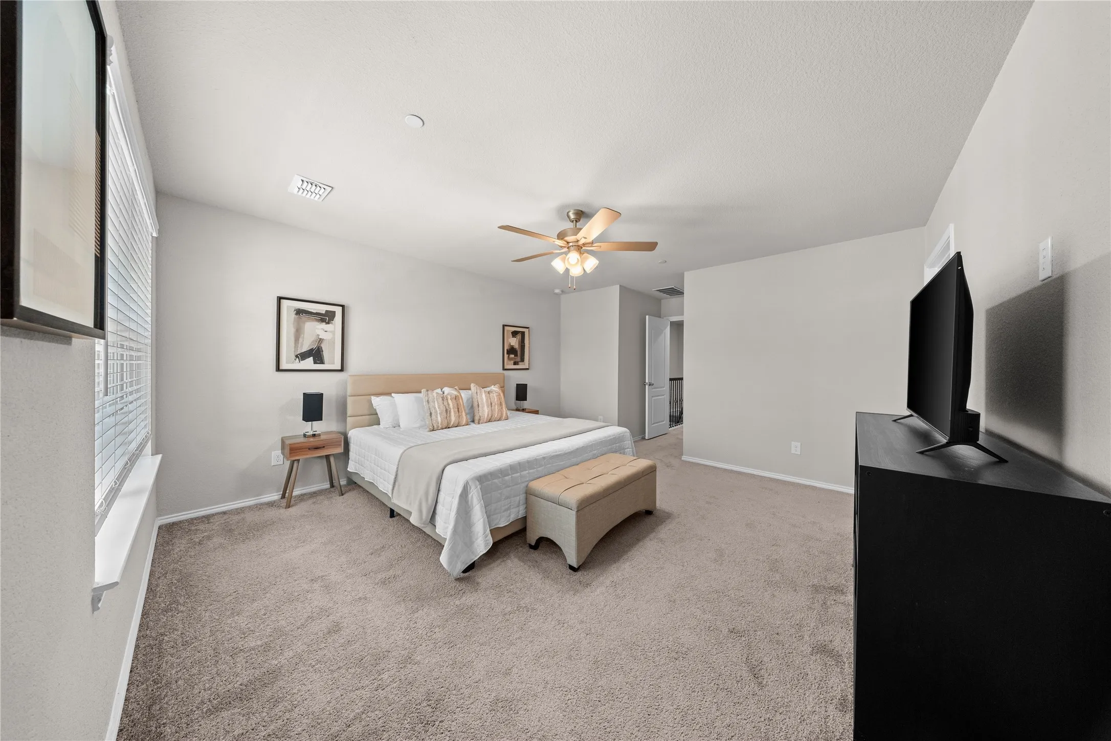 Spacious room featuring vaulted ceilings, neutral-toned carpeting, a ceiling fan with integrated lighting, and multiple windows with blinds