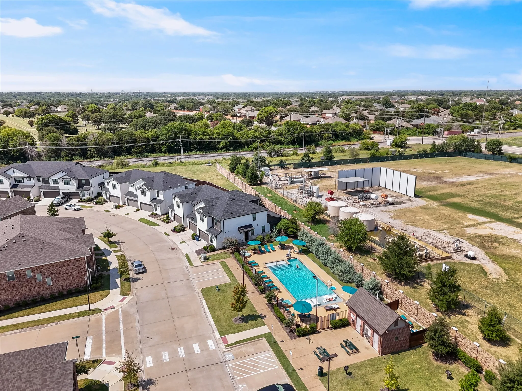 Community swimming pool with surrounding lounge chairs and umbrellas, featuring a dedicated pool house
