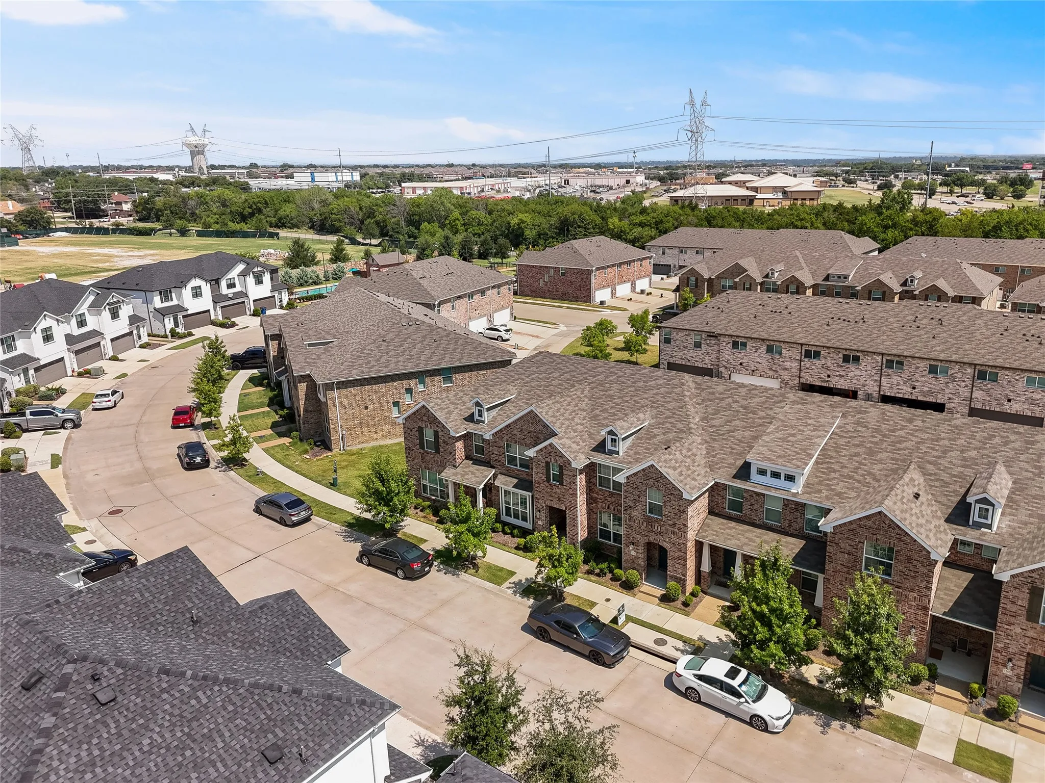 Curved streetscape featuring a mix of brick and siding townhomes with attached garages and gabled roofs