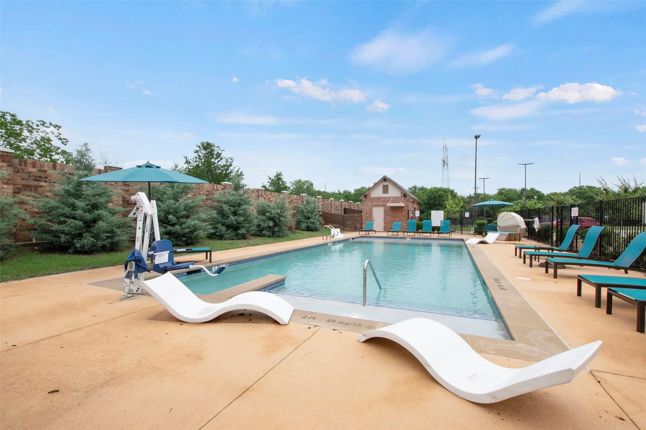 Outdoor swimming pool featuring a concrete deck surround, integrated steps, and a perimeter fence