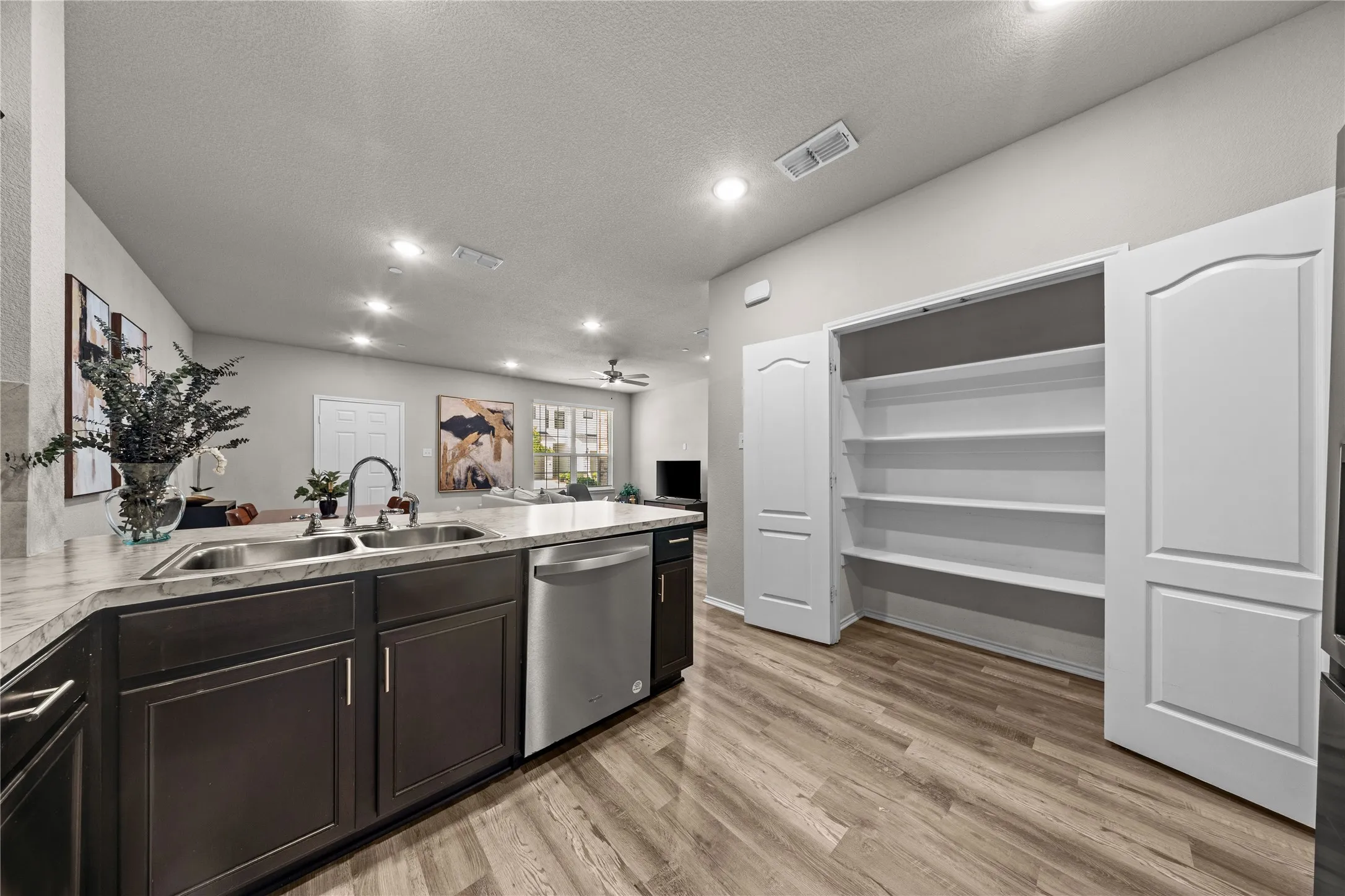 Spacious kitchen featuring dark cabinetry with stainless steel appliances, including a built-in dishwasher and island with integrated sink