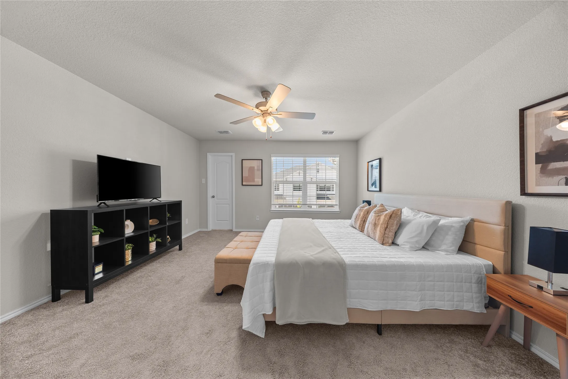 Spacious room featuring neutral carpeting, a ceiling fan with integrated lighting, and multiple windows
