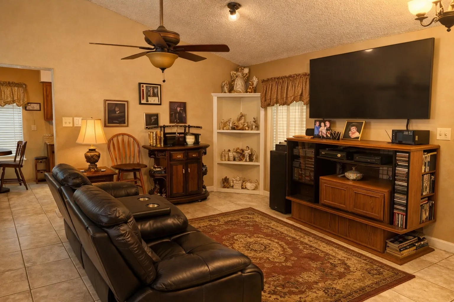 Living area featuring tile flooring, vaulted ceiling, and a ceiling fan with integrated lighting