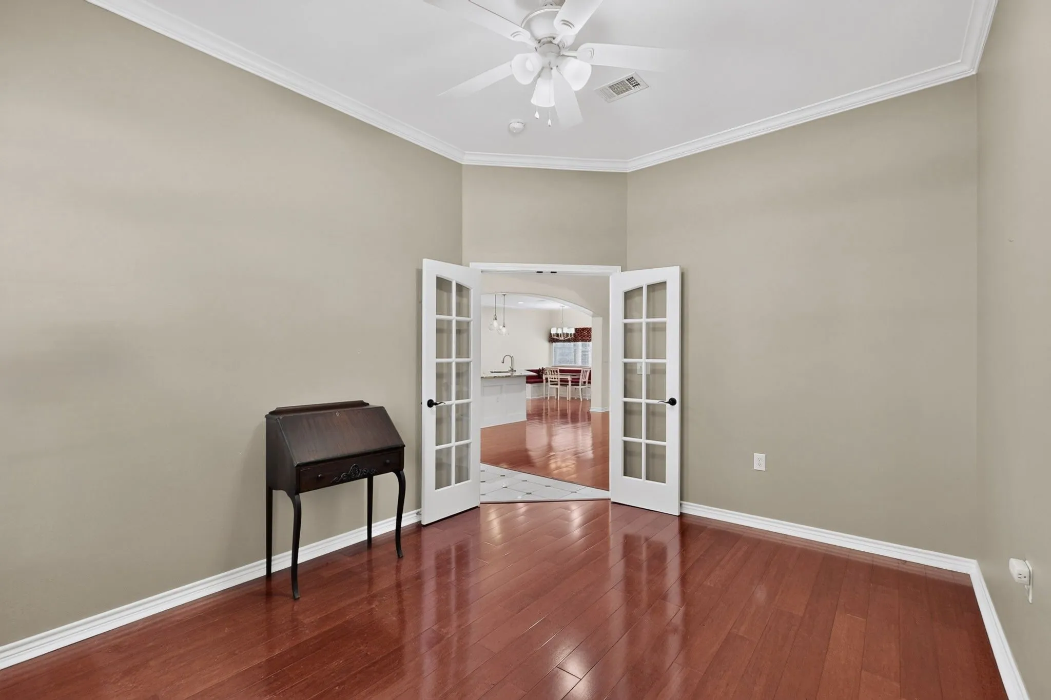 Interior room featuring wood-finish flooring, neutral wall paint, and white crown molding