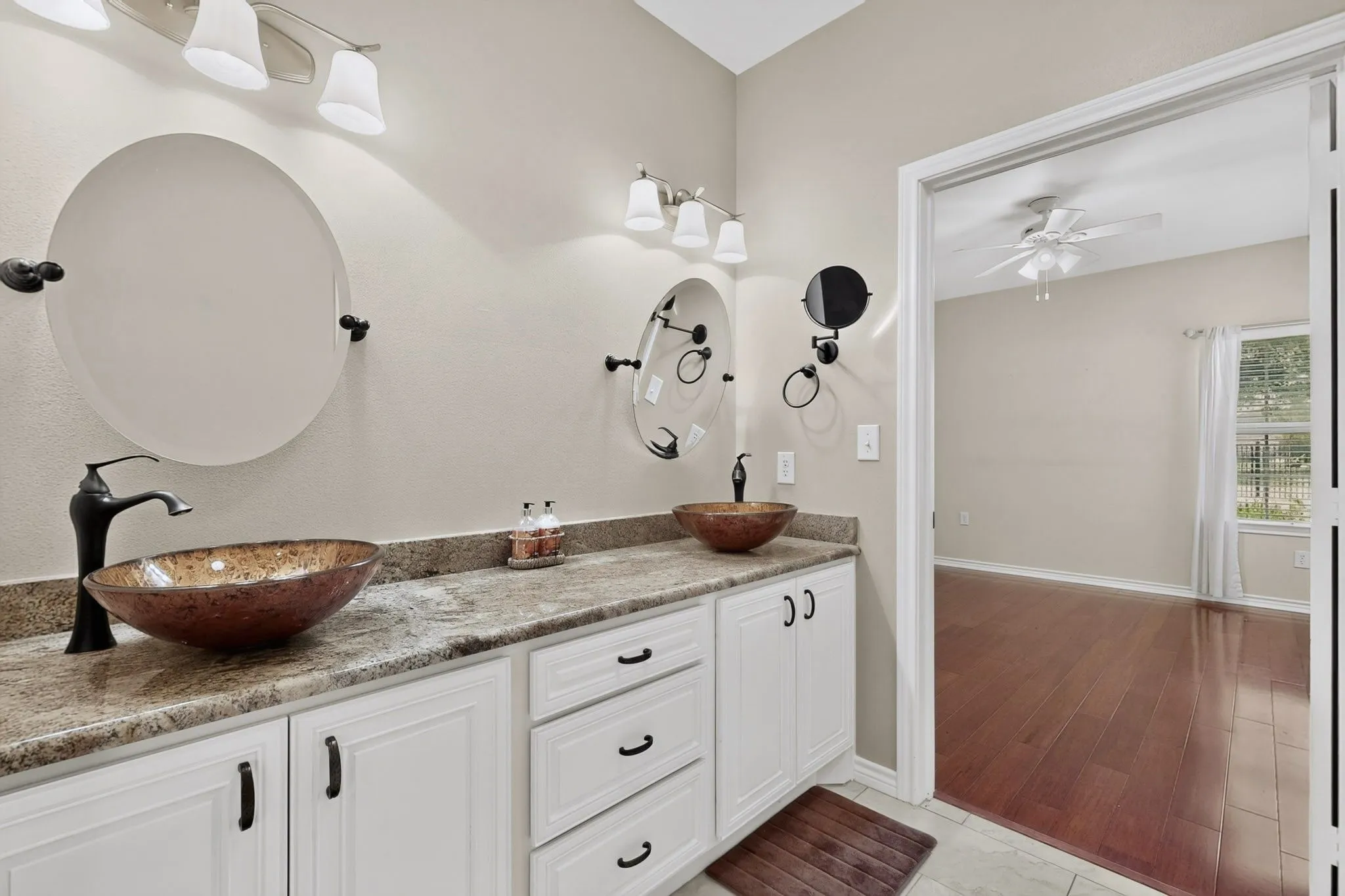 Double vanity with vessel sinks and countertop, featuring white cabinetry and wall-mounted light fixtures