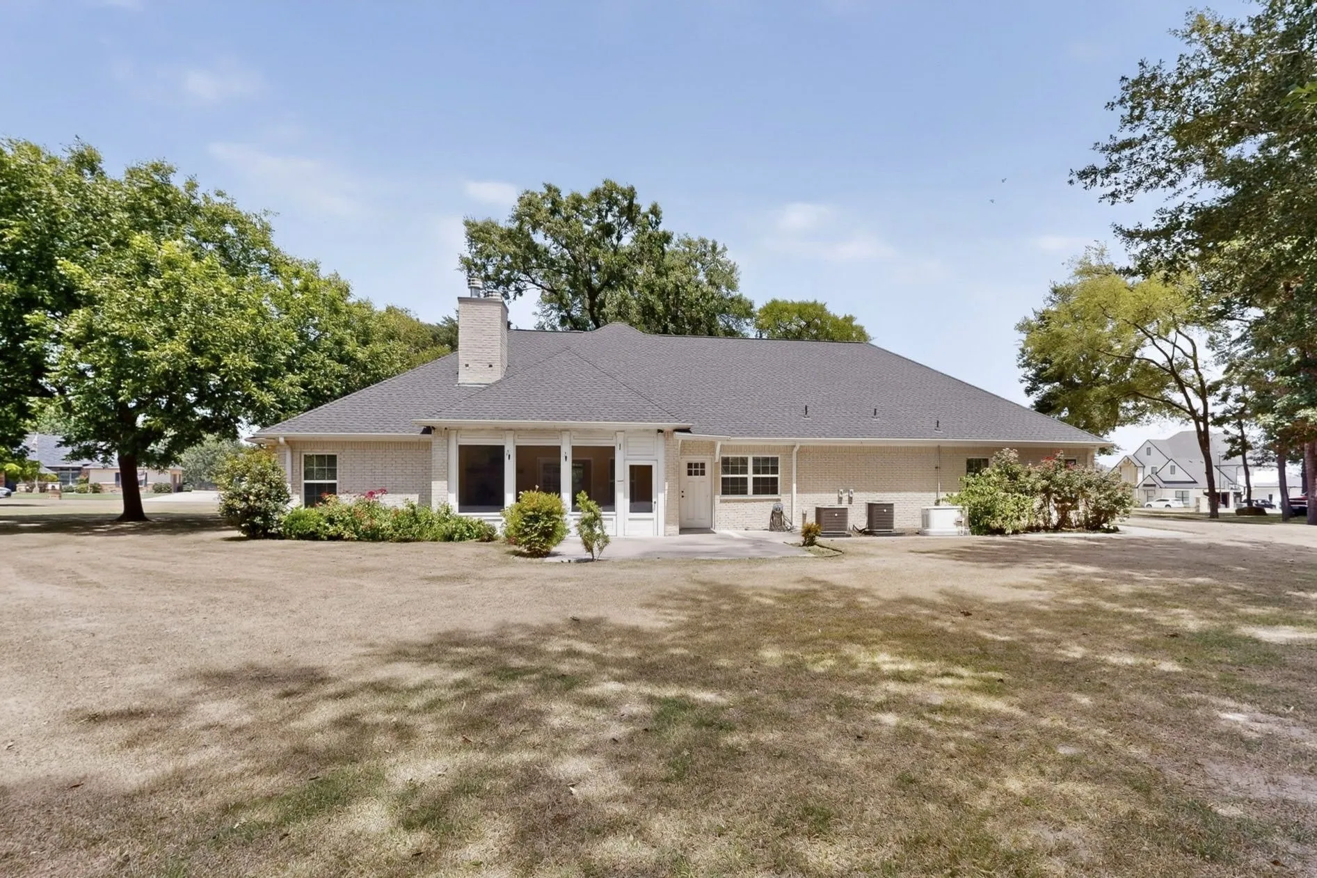 Beige brick exterior featuring a dark asphalt shingle roof