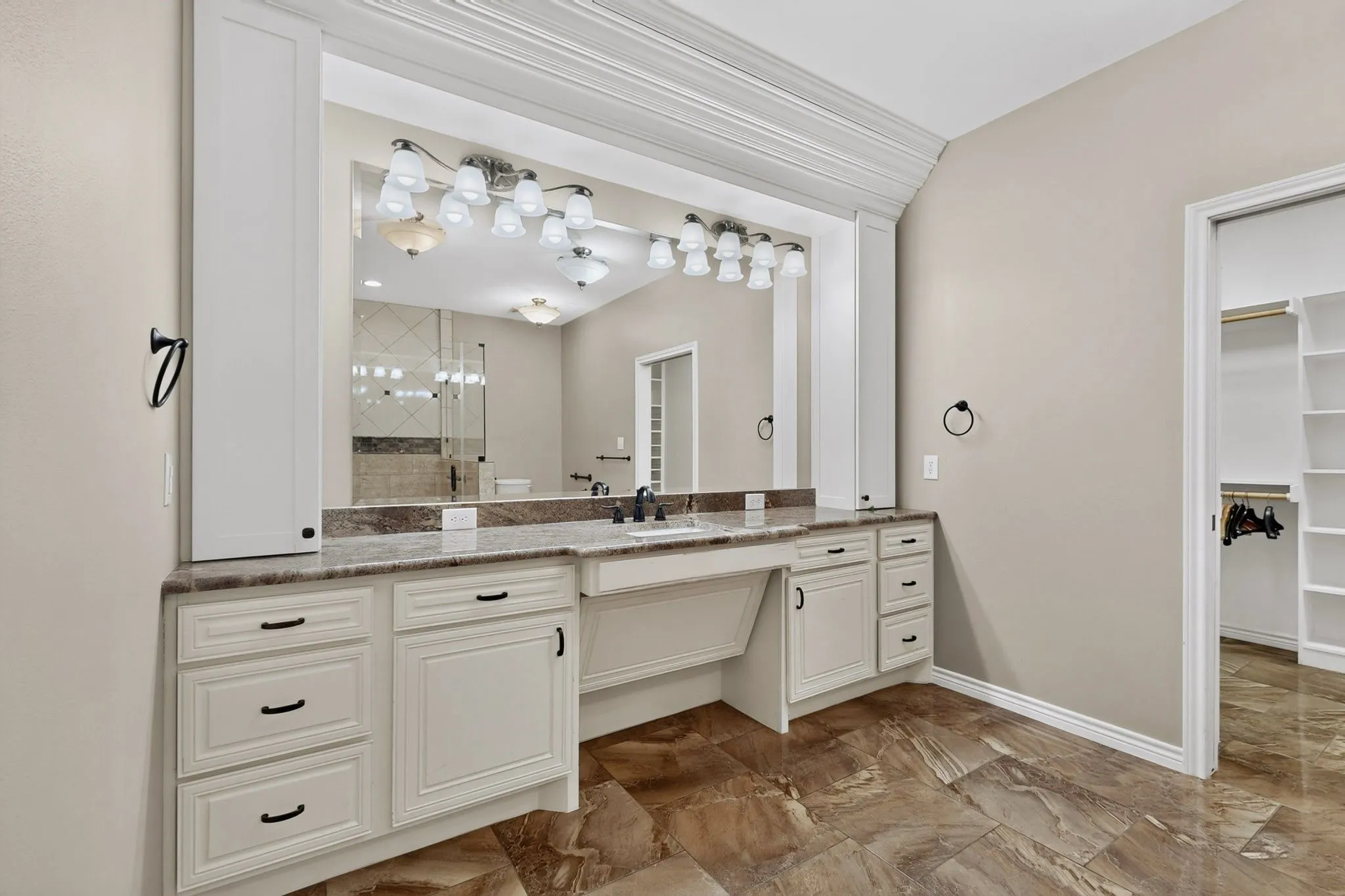 Vanity area featuring an integrated sink, dark countertop, and extensive built-in cabinetry with dark hardware