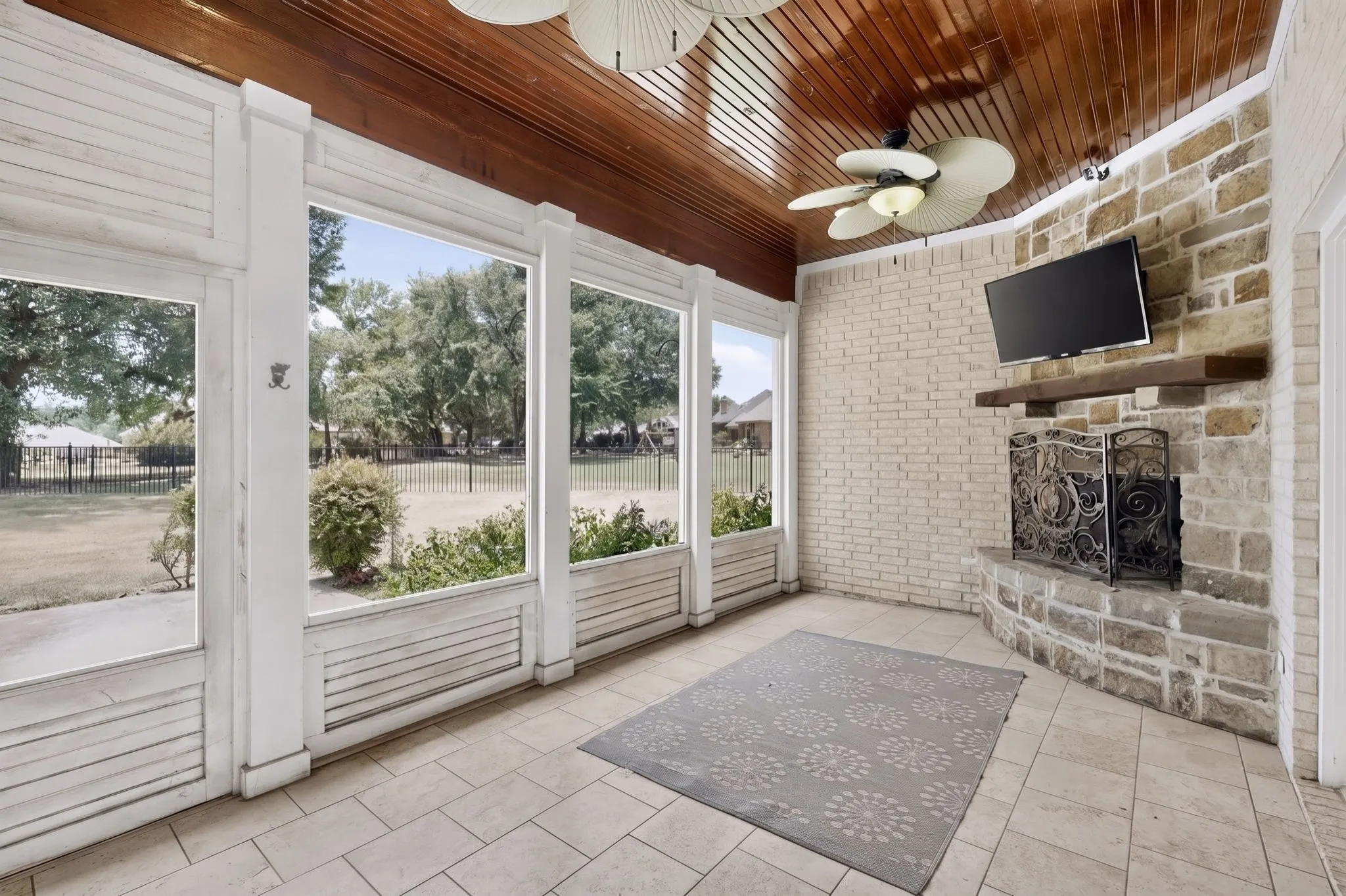 Screened porch featuring a natural stone fireplace, a decorative iron fire screen, and a wood mantel