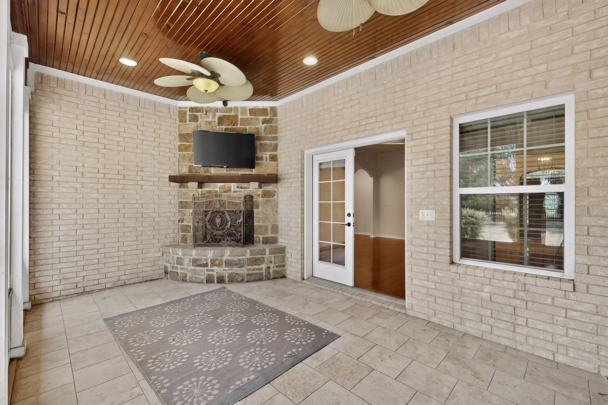 Screened patio featuring a corner fireplace with stone surround and wood mantel