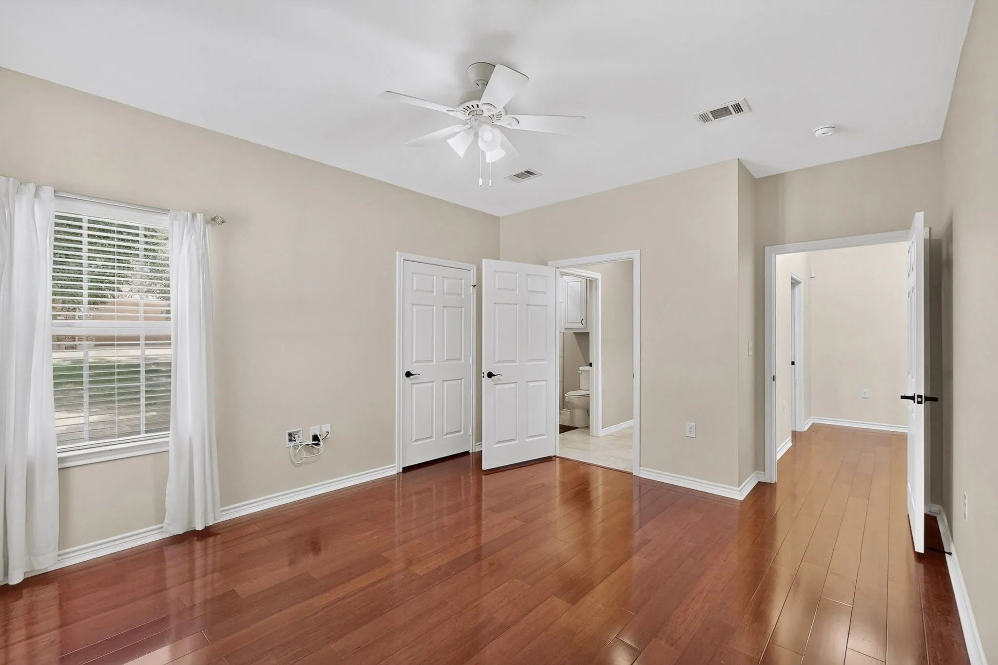 Spacious interior featuring wood-finish flooring, light neutral wall tones, and a ceiling fan