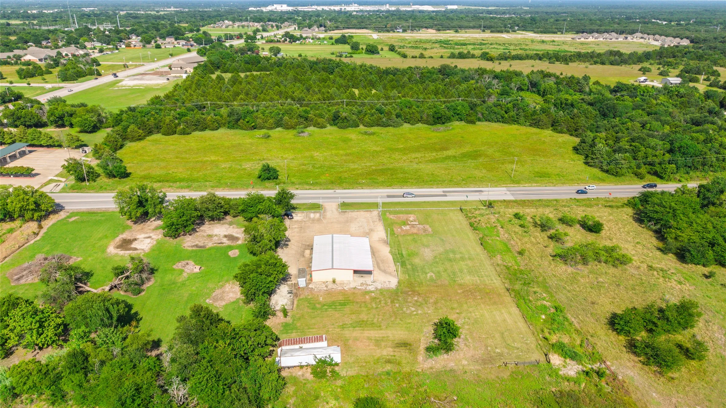 Expansive rural property featuring a large metal building, a prominent roadside location, and surrounding open land