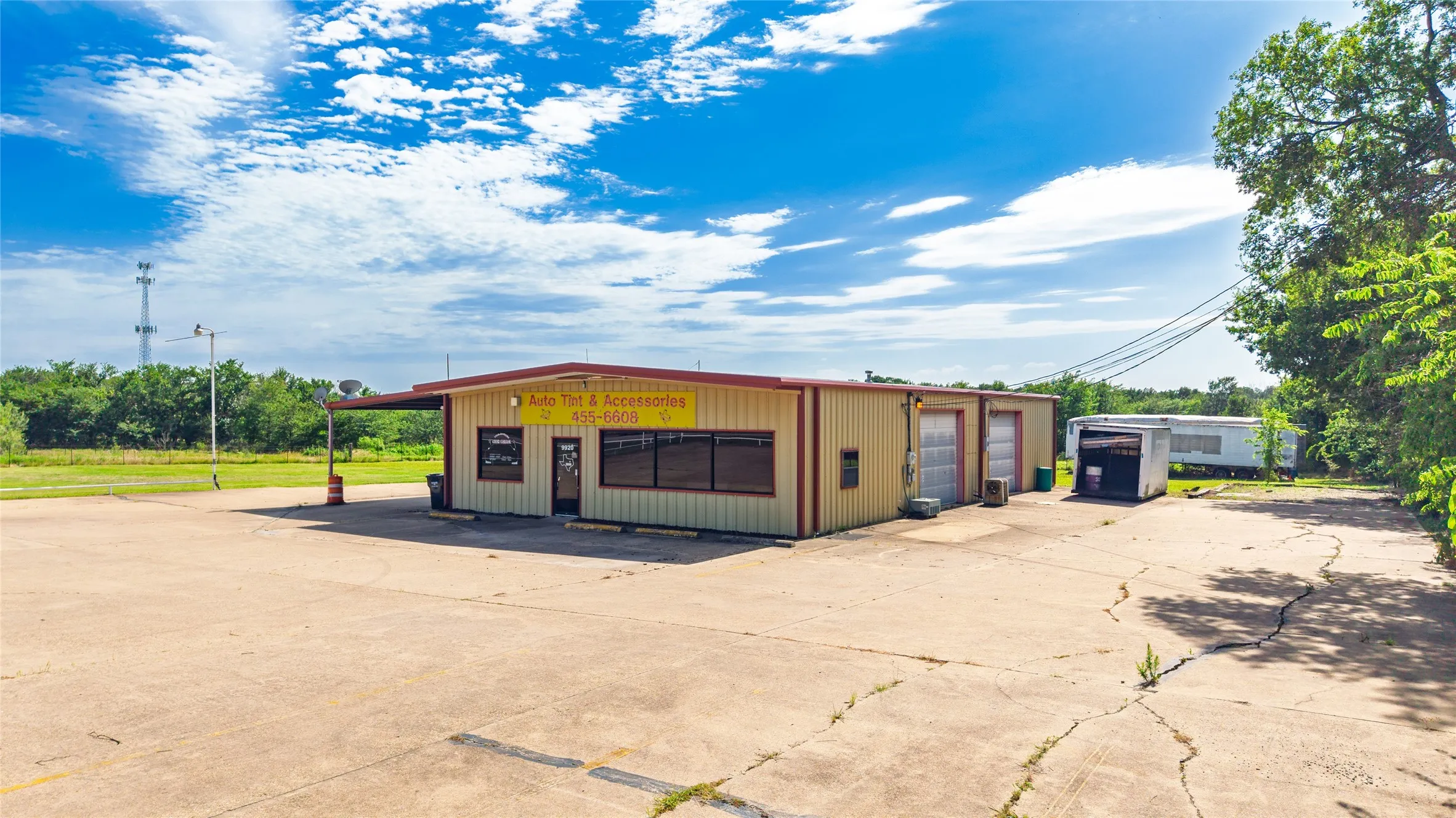 Commercial building with a metal exterior, multiple bay doors, an attached covered canopy, and a concrete parking area