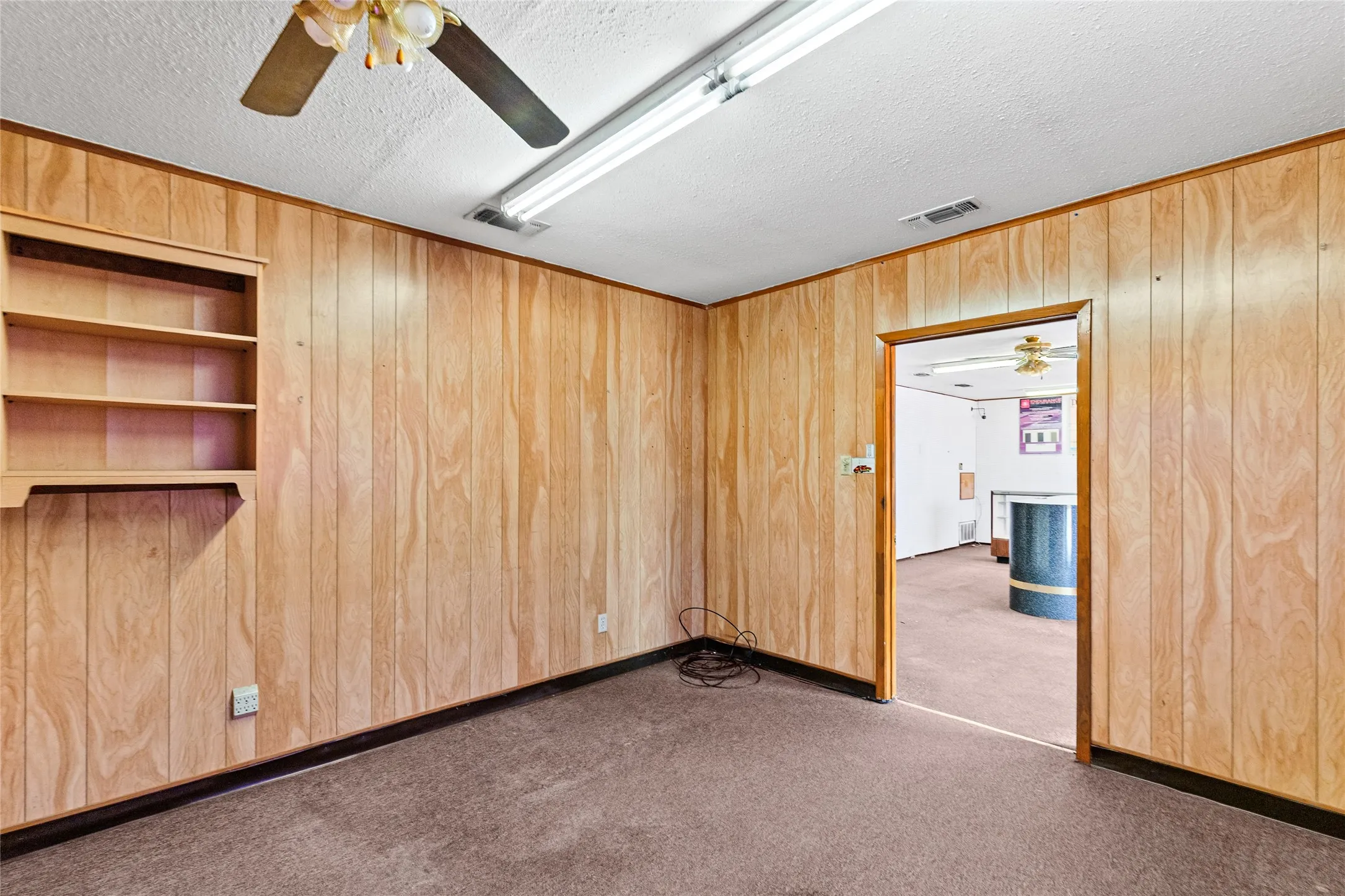 Room featuring wood-paneled walls, a drop ceiling, and carpet flooring