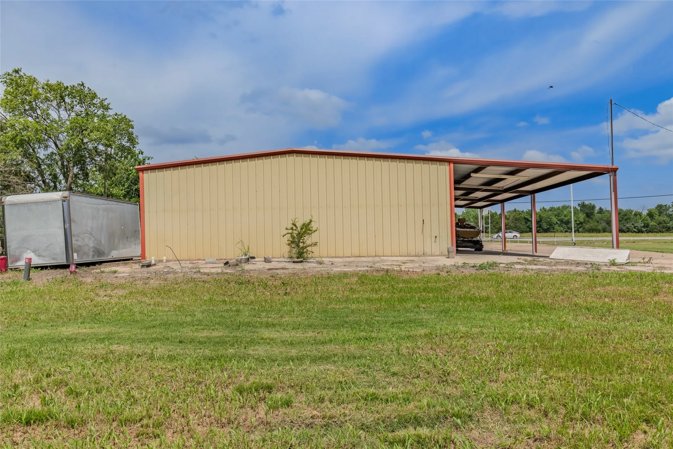 Metal building featuring a light-colored corrugated facade and red trim