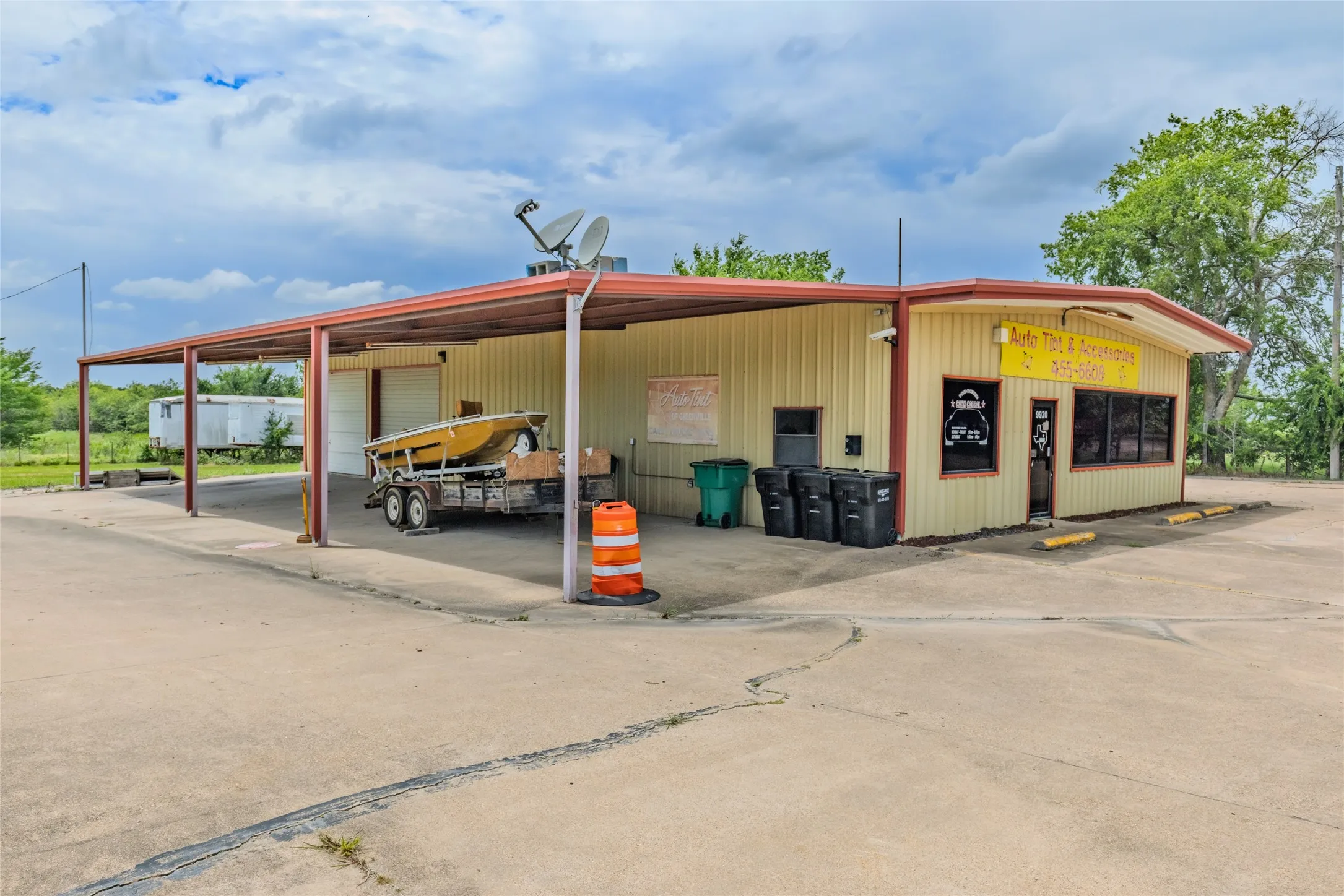 Commercial building featuring a covered carport, corrugated metal siding, and a concrete parking area