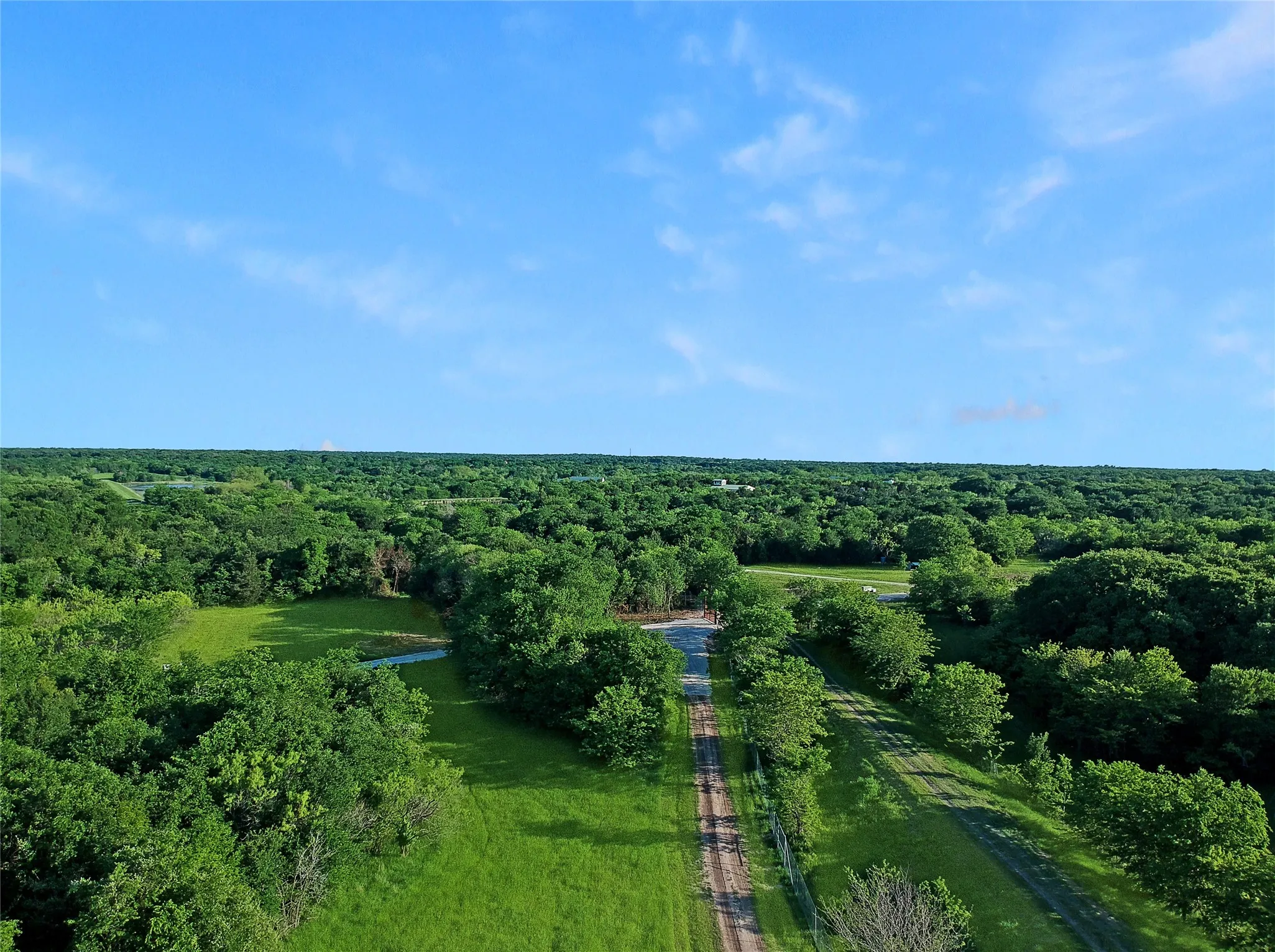 Expansive rural landscape featuring a private drive, verdant green spaces, and mature tree coverage