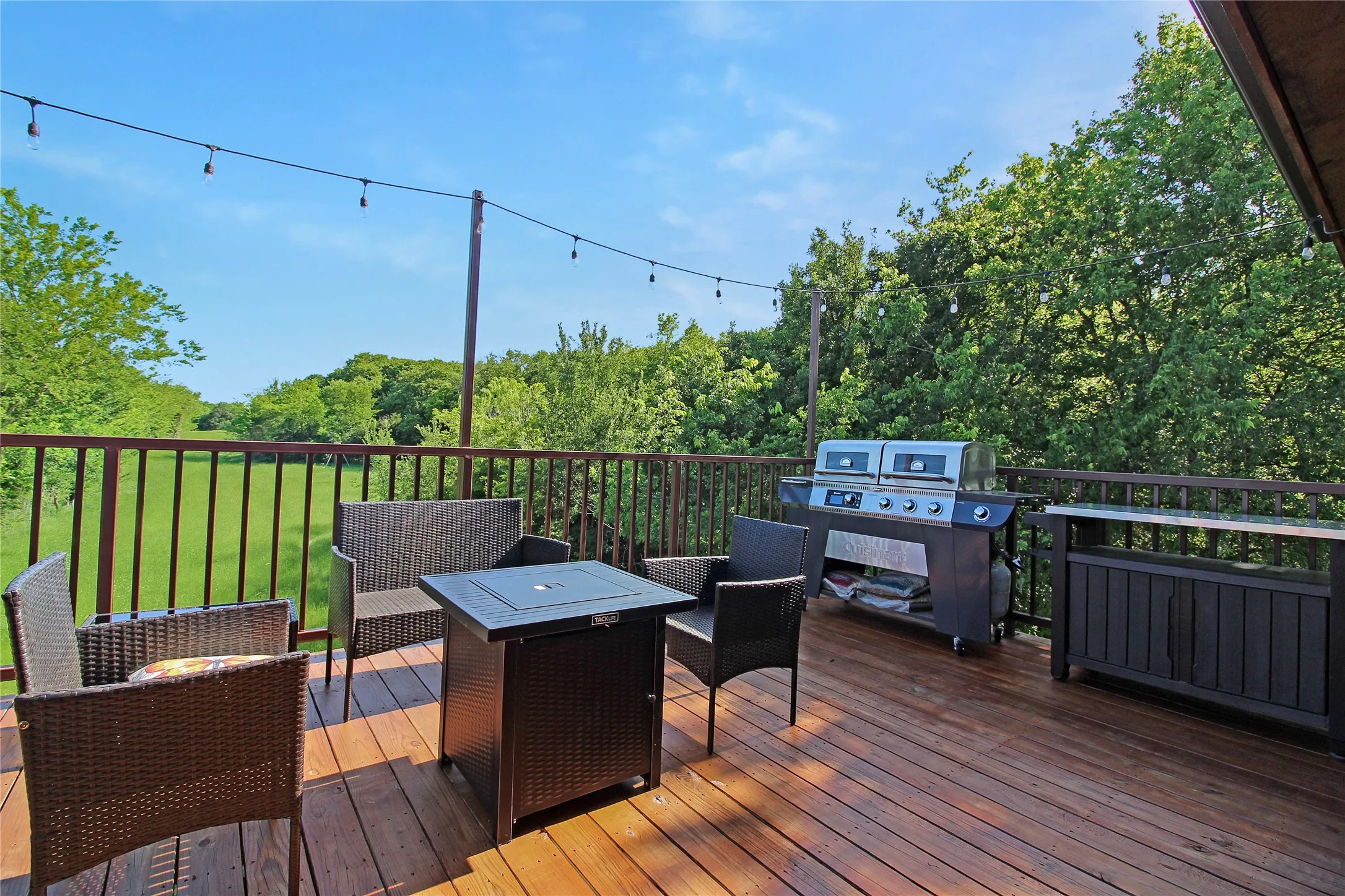 Expansive wood-finish deck with a brown railing, featuring string lighting overhead