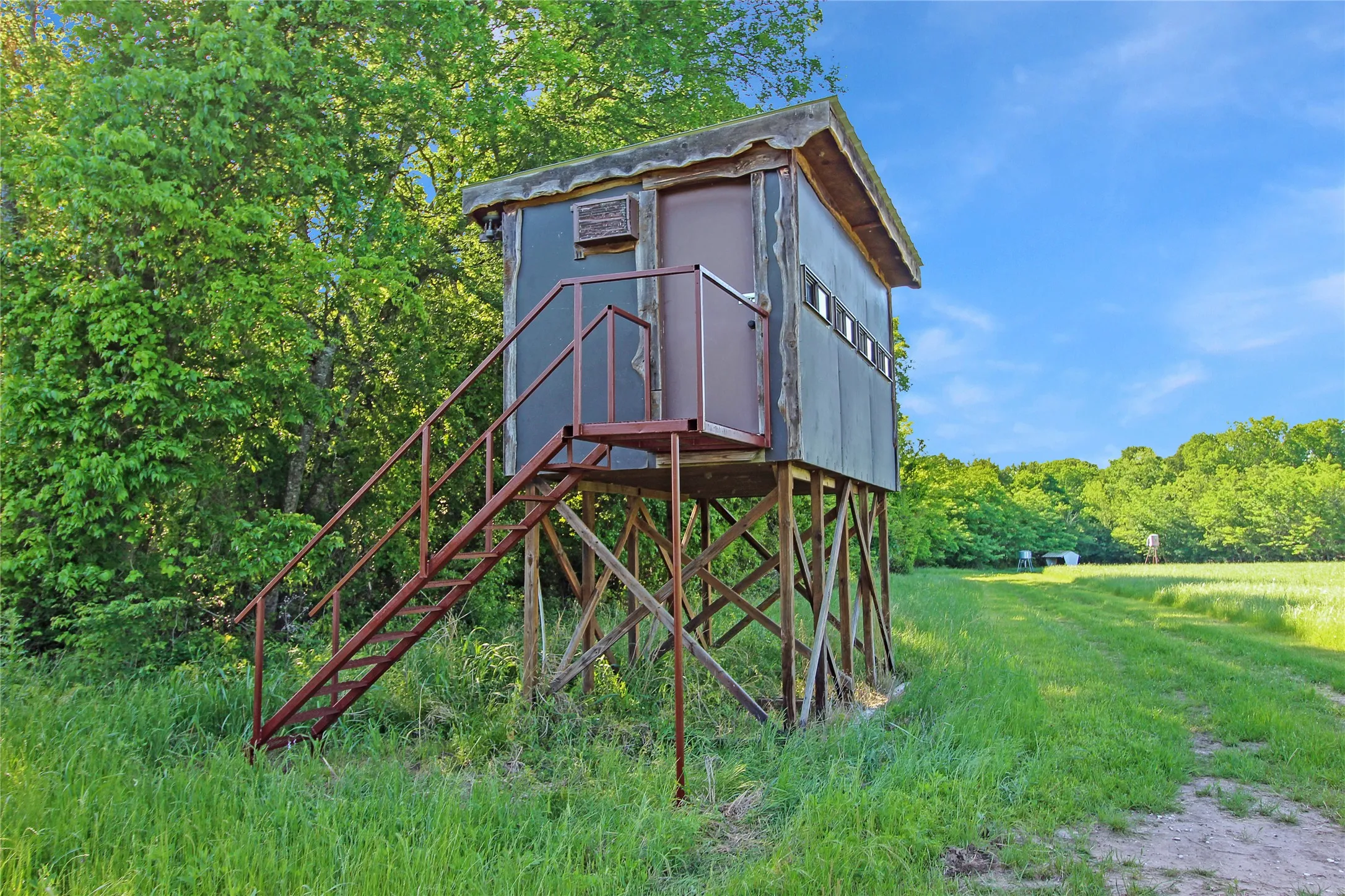 Elevated structure with a metal exterior and a flat roof, featuring a metal entry door and horizontal window openings